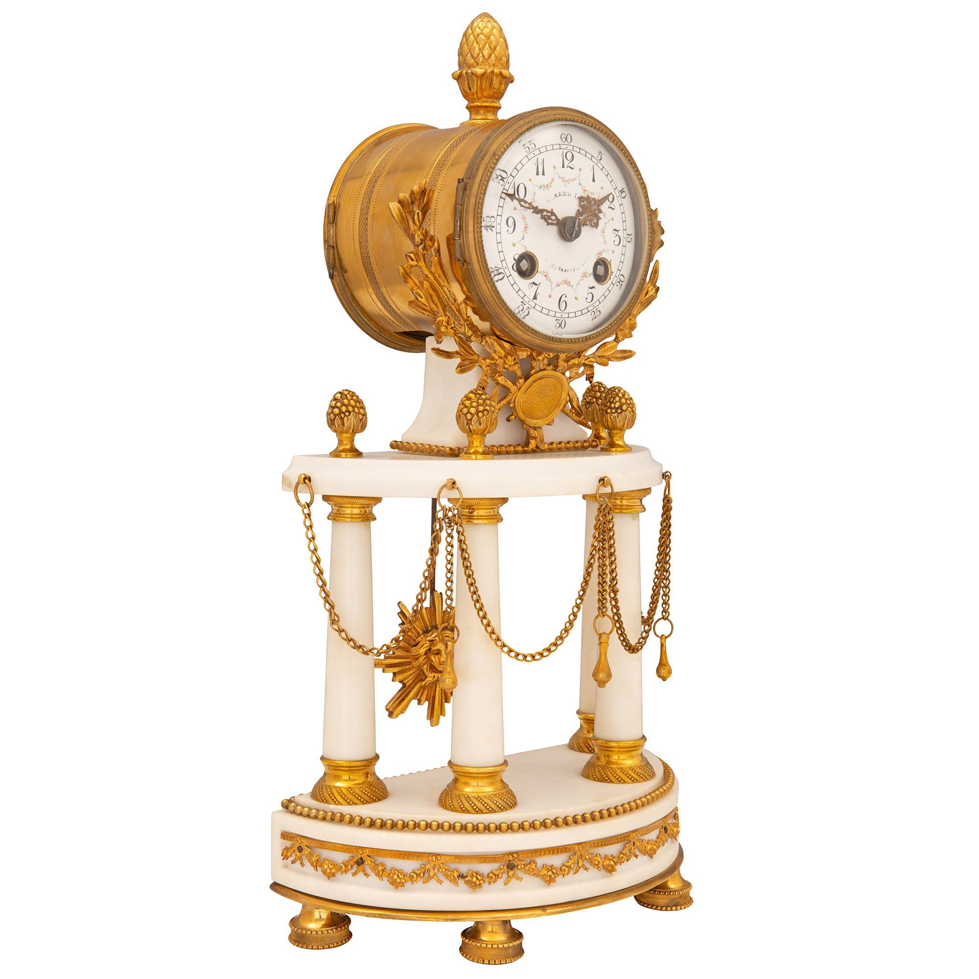 Elegante orologio francese del XIX secolo in stile Luigi XVI in ormolu e marmo bianco di Carrara. L'orologio è sollevato da raffinati supporti circolari in ormolu sotto la base in marmo bianco di Carrara a forma di demi lune, decorata con bellissime