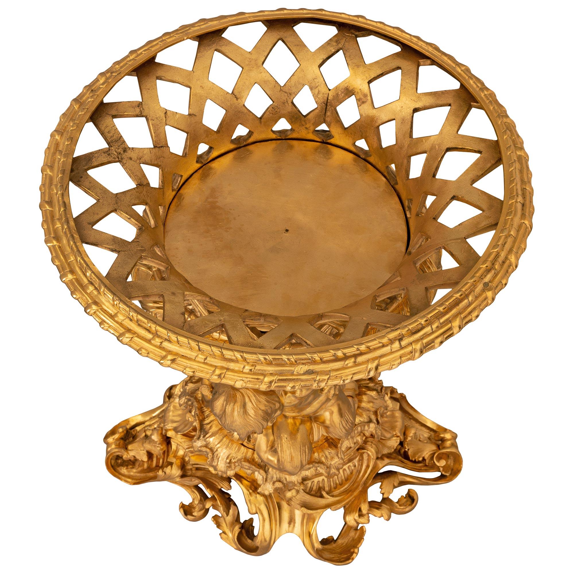 A stunning and extremely high quality French 19th century Louis XVI st. ormolu centerpiece attributed to Henry Dasson. The centerpiece is raised by an exceptional and most decorative pierced base with most decorative scrolled foliate movements in a