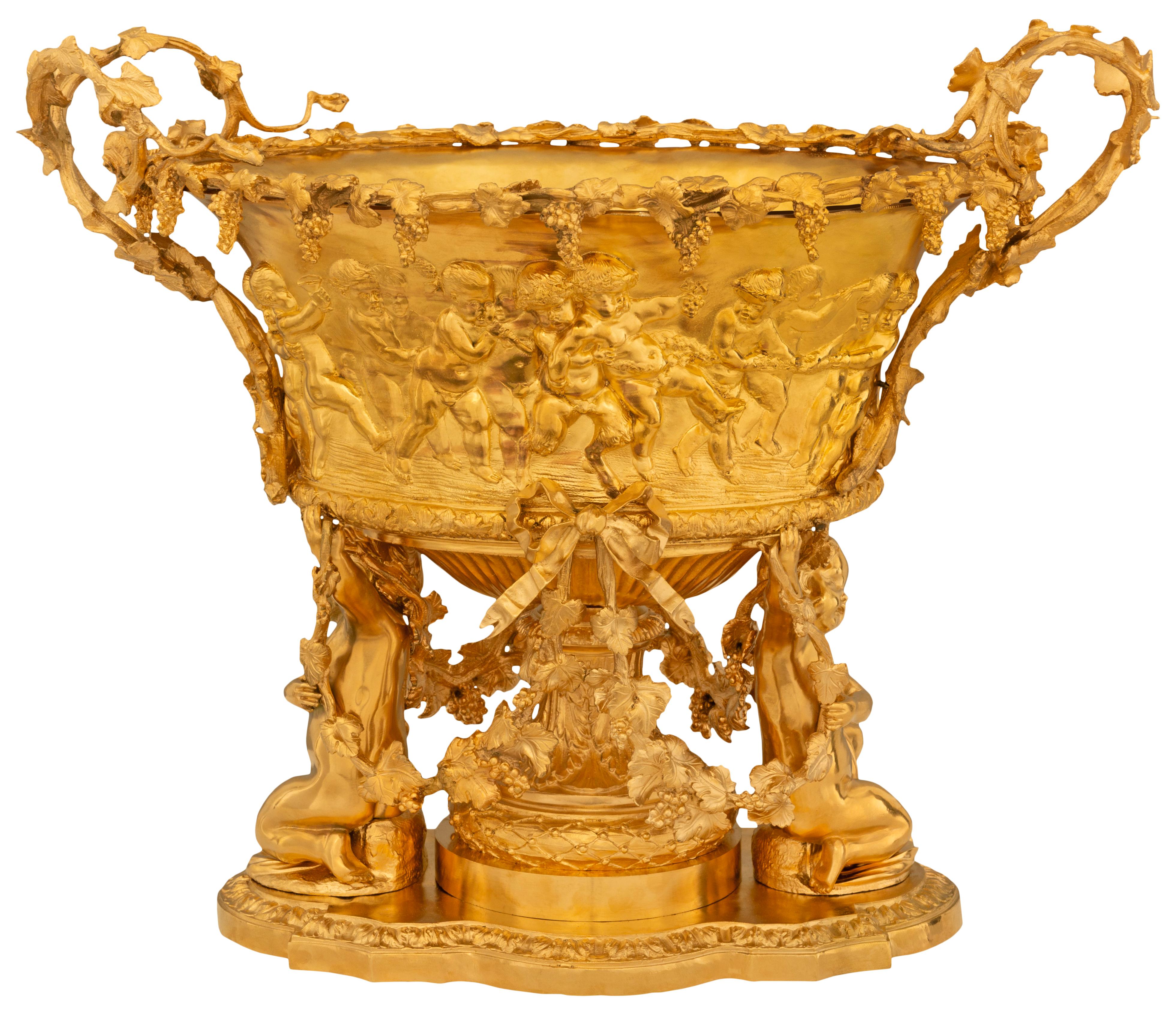 An elegant most decorative French 19th century Louis XVI st. Ormolu centerpiece. This stunning centerpiece is raised on a socle shaped pedestal with berried laurel vines, acanthus leaves, swaging foliate garlands, and a cherub on either side. The