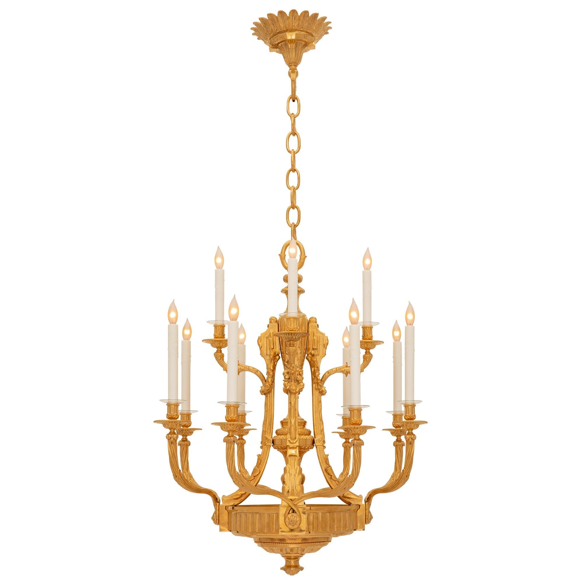 Magnifique lustre en bronze doré de style Louis XVI du XIXe siècle. Le lustre à douze bras et à deux niveaux est centré par un fin fleuron inférieur à fines feuilles tachetées, sous de belles feuilles de laurier enrubannées, sous des bandes