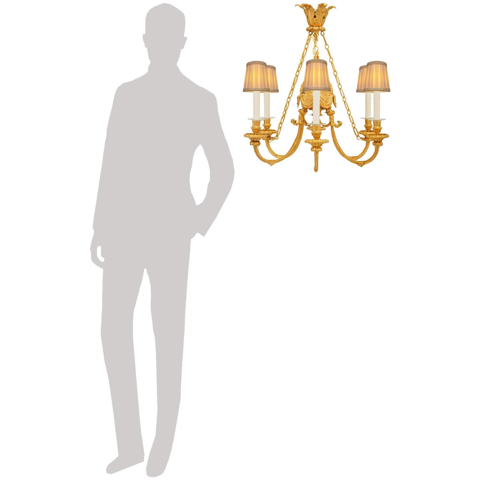 Un elegante e pregiato lampadario francese del XIX secolo in stile Luigi XVI in Ormolu. Questo meraviglioso lampadario a sei bracci e sei luci è centrato da una splendida cupola riccamente cesellata e arricchita da tessuti drappeggiati alla base e