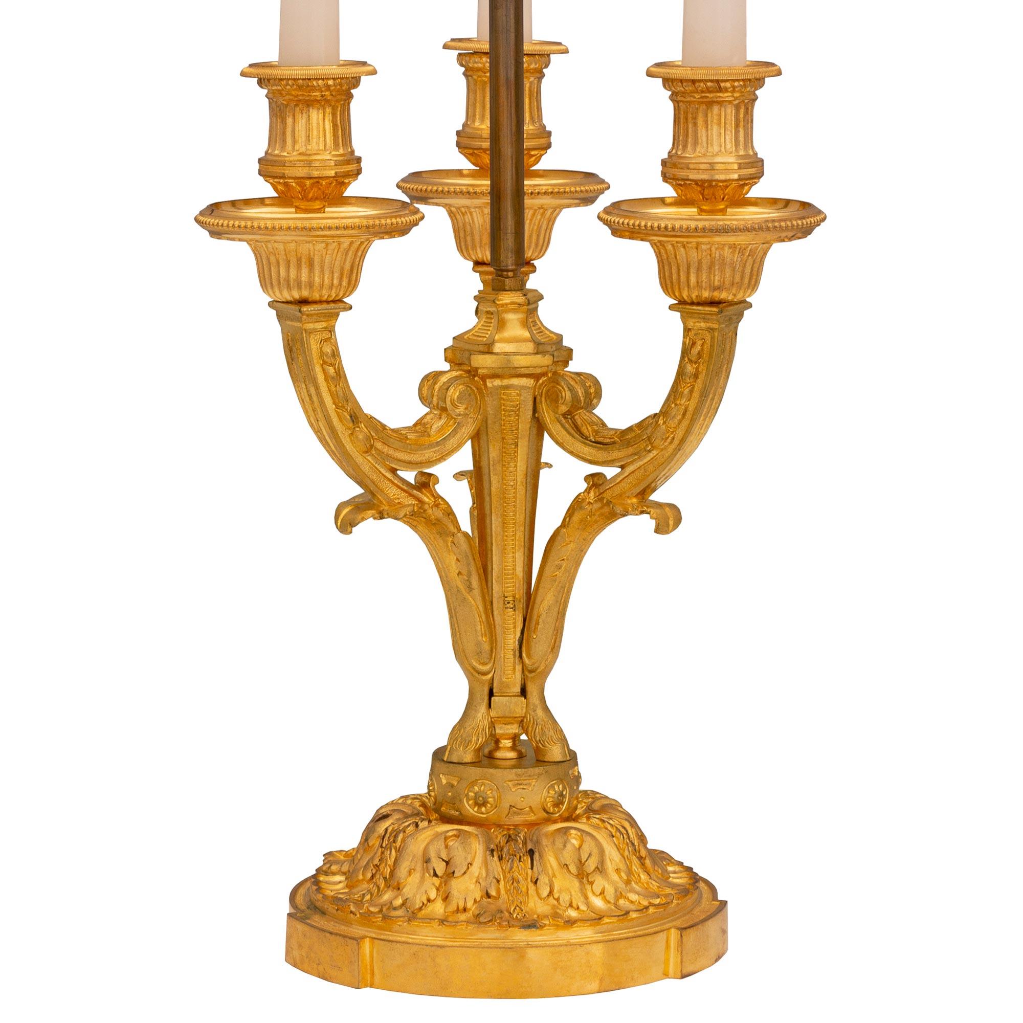An elegant French 19th century Louis XVI st. ormolu lamp. The three armed lamp is raised by a fine circular mottled base with large beautiful richly chased acanthus leaves. At the center are three lightly curved scrolled supports adorned with