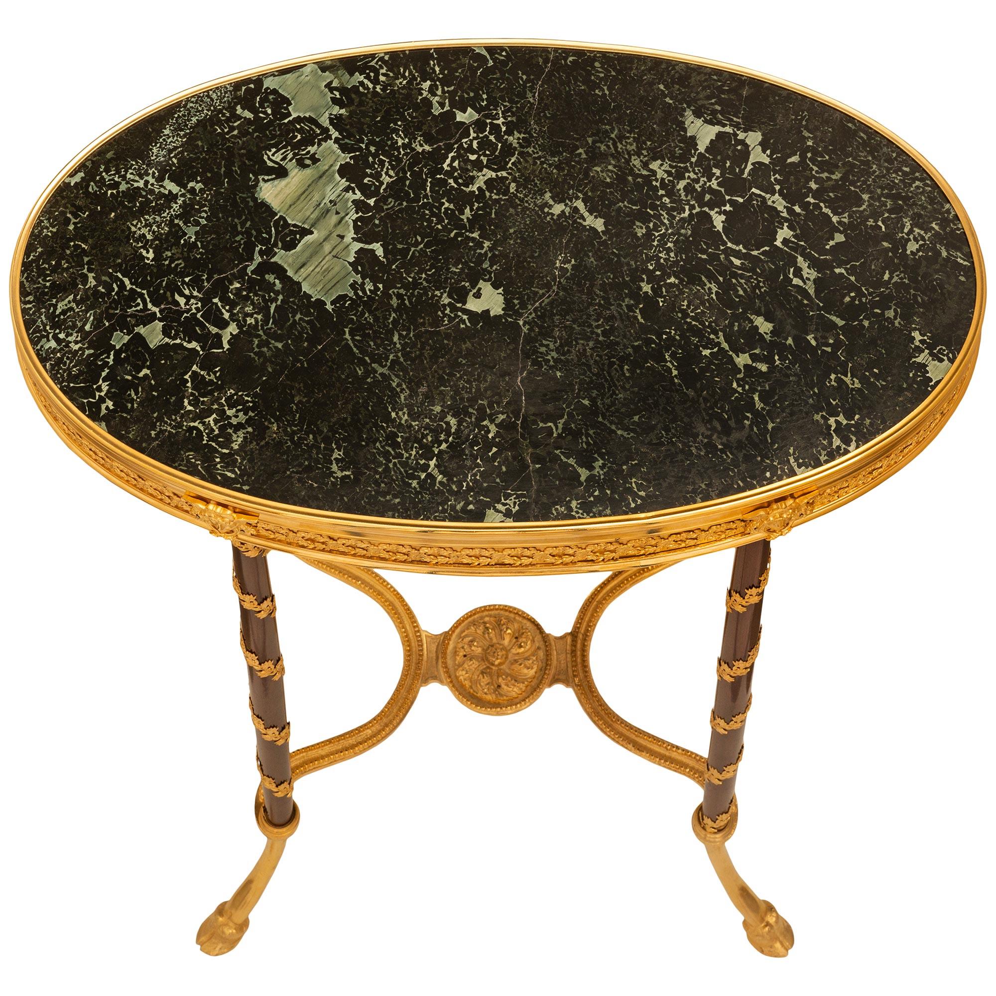 Eine sehr elegante Französisch 19. Jahrhundert Louis XVI st. Ormolu, Mahagoni und Marmor Tisch. Der ovale Beistelltisch steht auf vier C-förmig geschwungenen Ormolubeinen, die mit Huffüßen enden. Die vier Beine sind durch einen X-förmigen Keilrahmen