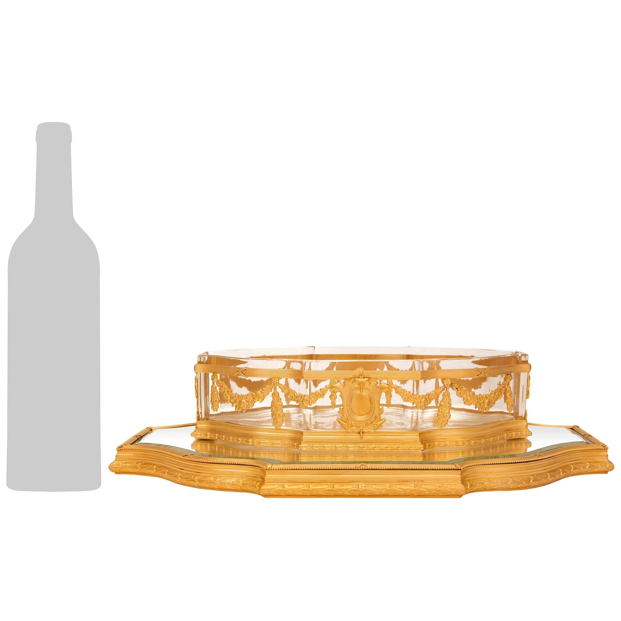 Un élégant et très décoratif centre de table en bronze doré, miroir et cristal de style Louis XVI du 19ème siècle. Ce joli centre de table en forme de coquille Saint-Jacques est présenté sur un magnifique plateau en miroir biseauté. Le plateau est