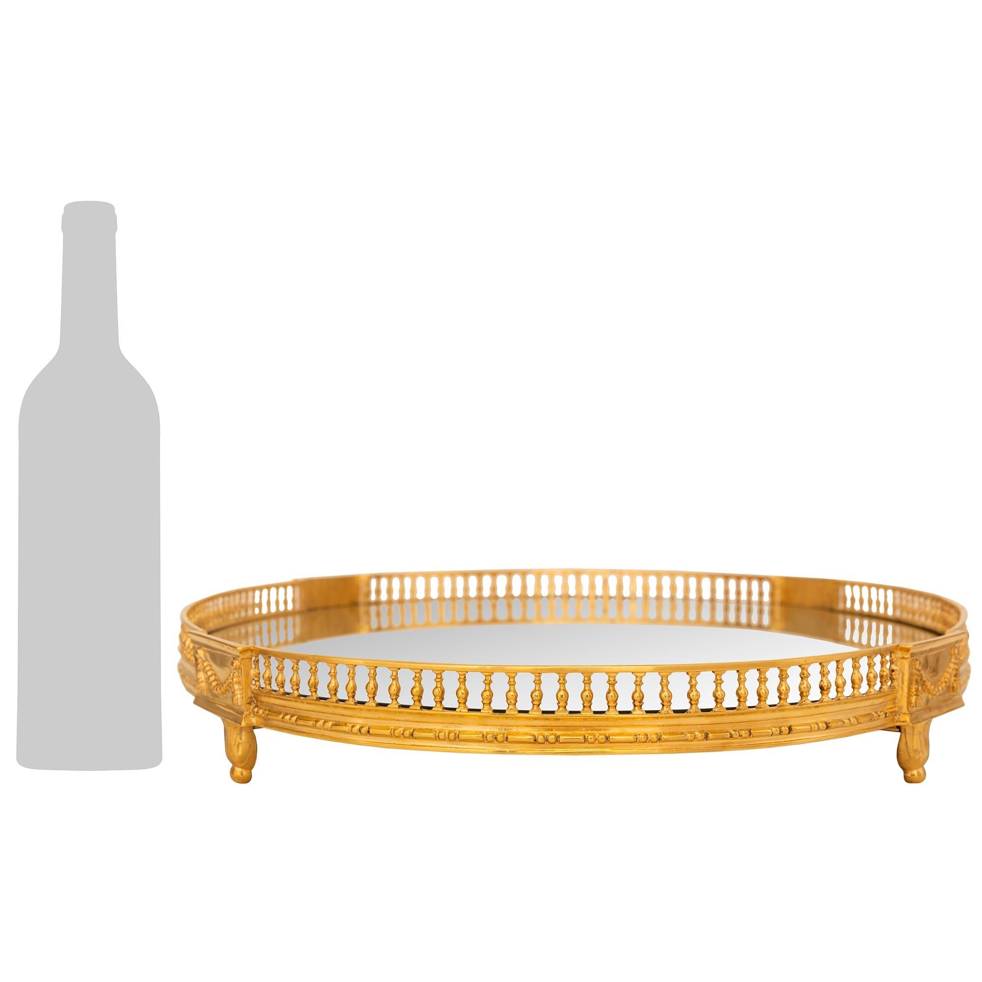 Un exquis et très élégant plateau de centre de table en bronze doré de style Louis XVI du XIXe siècle. Ce magnifique centre de table est surélevé par de fins pieds feuillagés sous de jolies guirlandes de perles et de glands. Une délicate bande