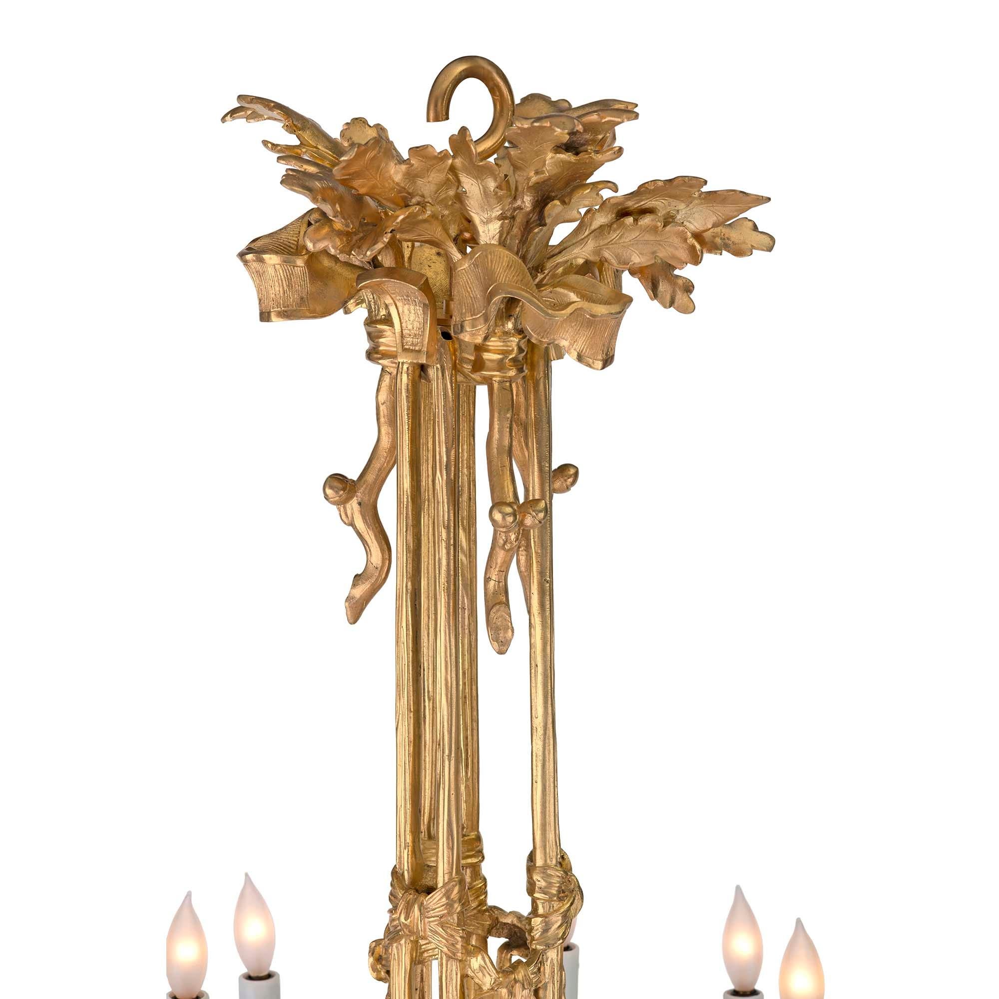 A spectacular French 19th century Louis XVI st. ormolu twelve light chandelier. At the base are tied tassels below impressive hoof designs. Centered are six impressive horn styled arms tied with ribbons interspersed with finely chased foliate