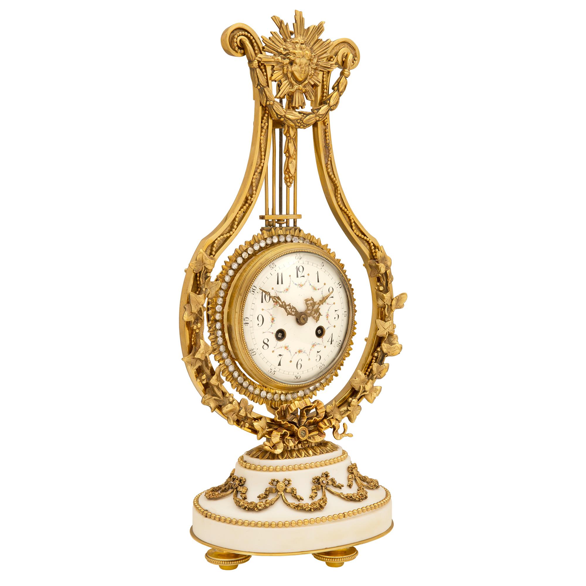 A most exquisite French mid-19th century Louis XVI st. ormolu, white Carrara marble and crystal clock. The clock is raised on a moulded oval white Carrara marble base supported by richly chased beaded topie shaped feet. Above and below the wrap