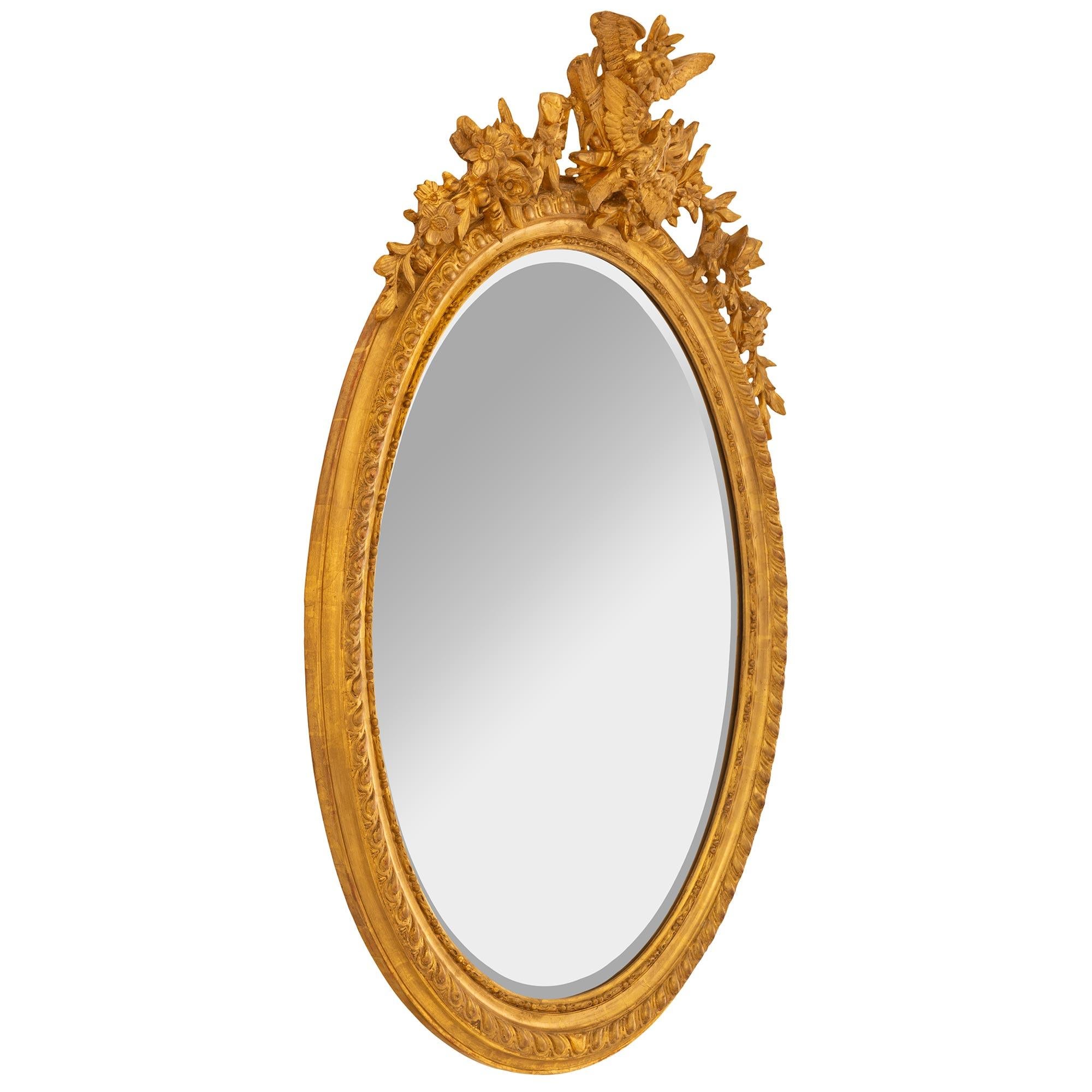 Très élégant miroir ovale en bois doré de style Louis XVI du XIXe siècle. La plaque de miroir est encadrée d'une jolie bordure perlée et mouchetée. Le bord est orné d'un fin motif de godrons torsadés qui se prolonge sur tout le cadre. Ci-dessus, la