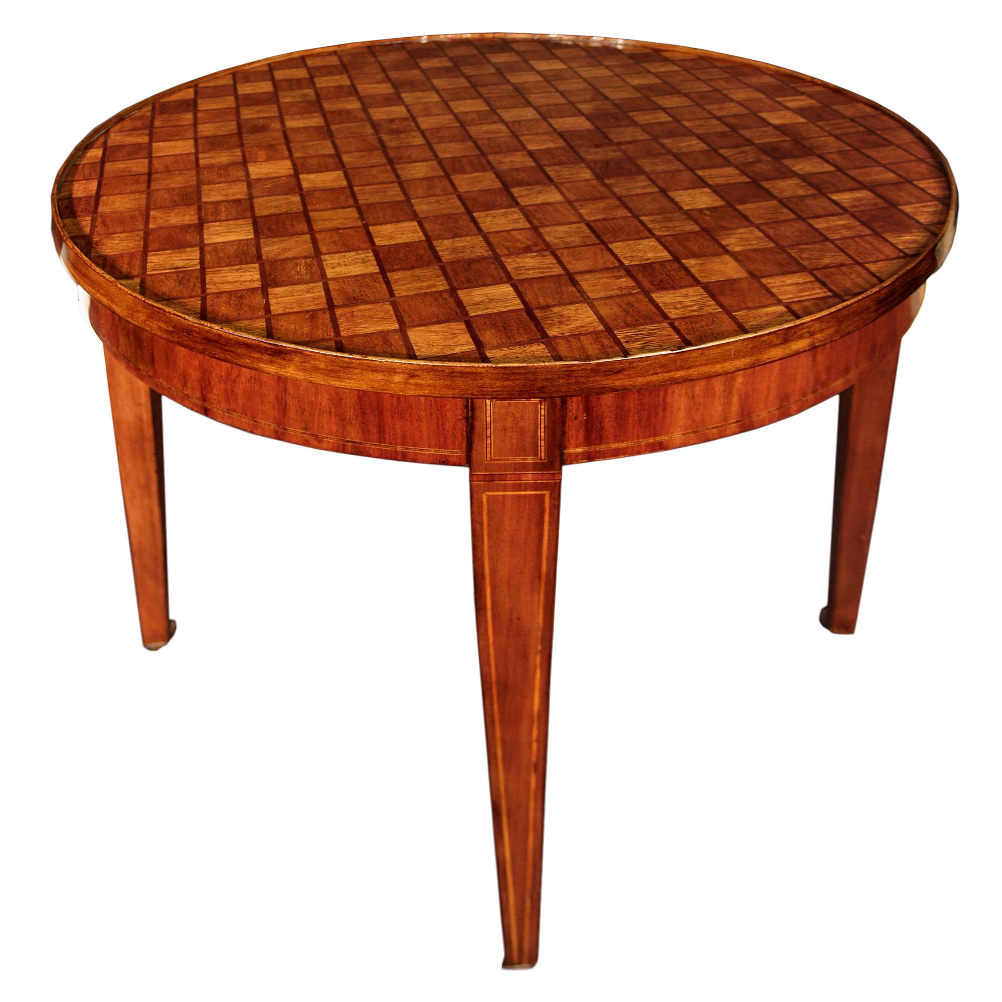 A French Louis XVI st. 19th century round tulipwood parquetry flip top center table. The table with square straight tapered legs raised by casters. The drum like apron is inlaid with tulipwood and boxwood filettes. The top with an elegant parquetry