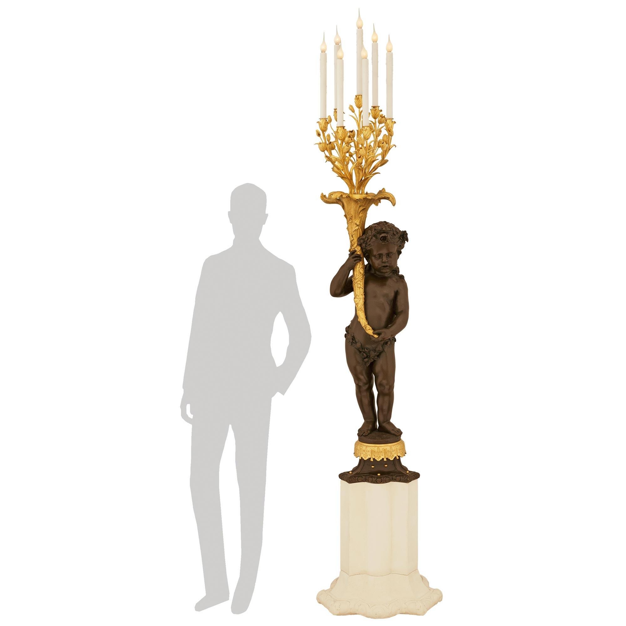 Eccezionale candelabro elettrificato francese del XIX secolo in bronzo patinato e Ormolu, di dimensioni monumentali. Questo candelabro è sollevato da un piedistallo a tricorno in pietra calcarea con disegni Rais-de-Coeur lungo la base, che sostiene