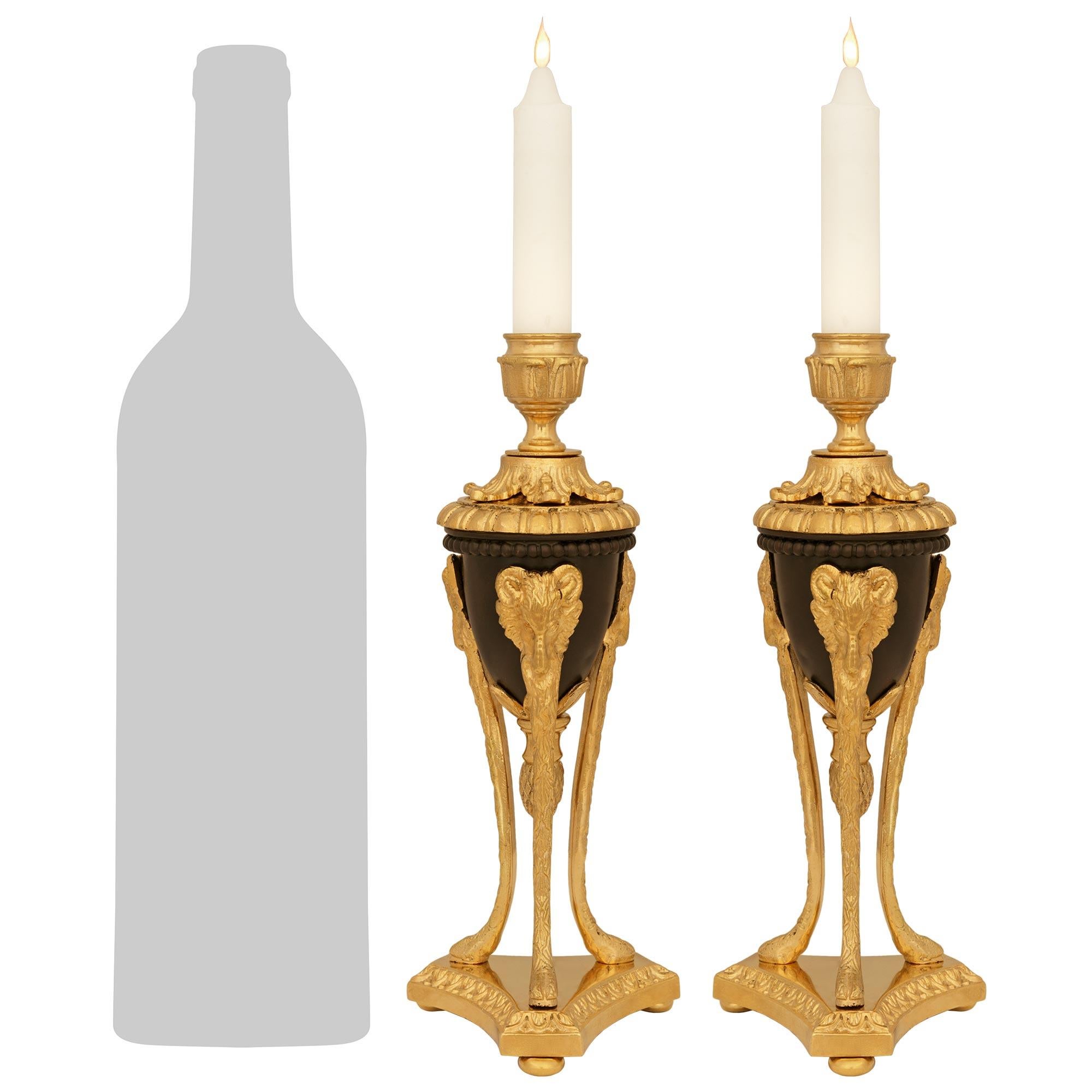 Ein elegantes und kleines Paar französischer Kerzenleuchter aus patinierter Bronze und Ormolu aus dem 19. Das Paar wird von dreieckigen Sockeln mit konkaven Seiten und Rais de Coeur-Oberkanten über den Kugelfüßen getragen. Darüber befinden sich drei