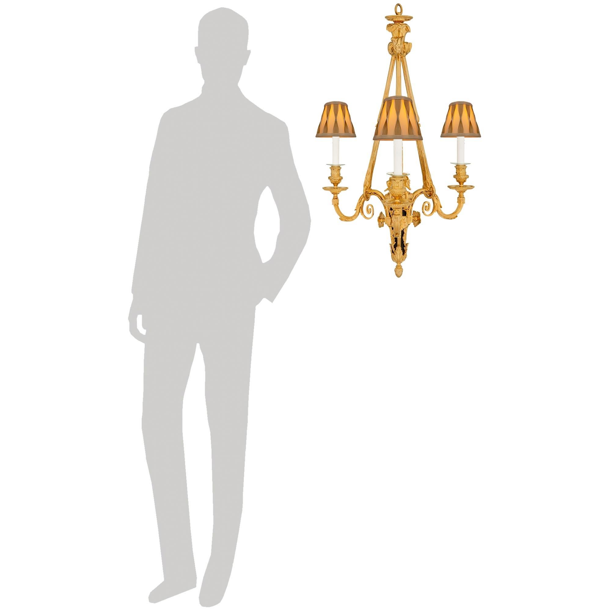 Un elegante lampadario francese del XIX secolo in bronzo patinato e Ormolu di alta qualità. Questo splendido lampadario a tre bracci, con un centro in bronzo patinato simile a una faretra, presenta meravigliose decorazioni a foglie d'acanto a volute
