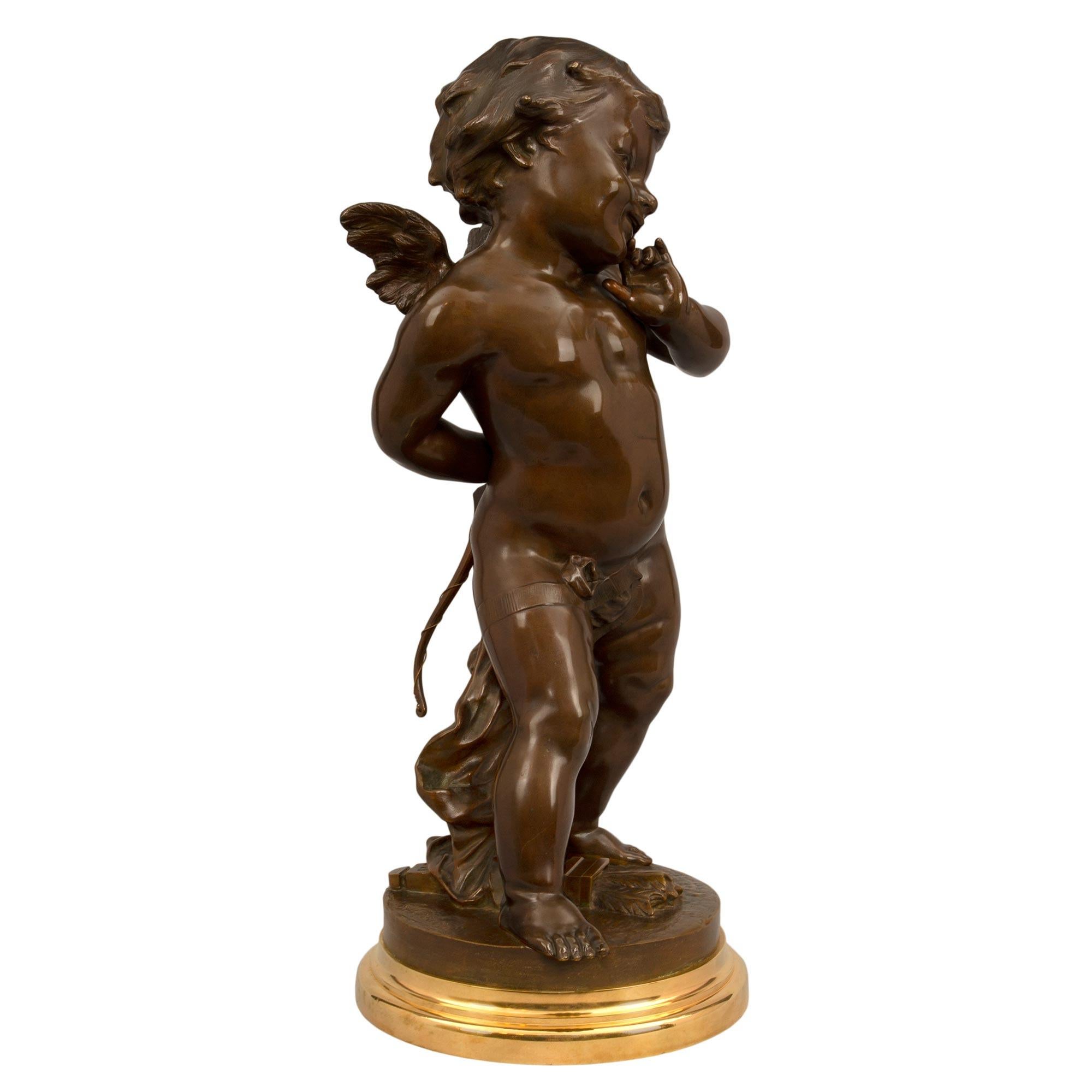 Charmante statue en bronze patiné et bronze doré de style Louis XVI du XIXe siècle, signée E. Drouot. La statue est surmontée d'une base circulaire en bronze doré avec une bordure tachetée. Le chérubin ailé finement détaillé, peut-être Cupidon, se