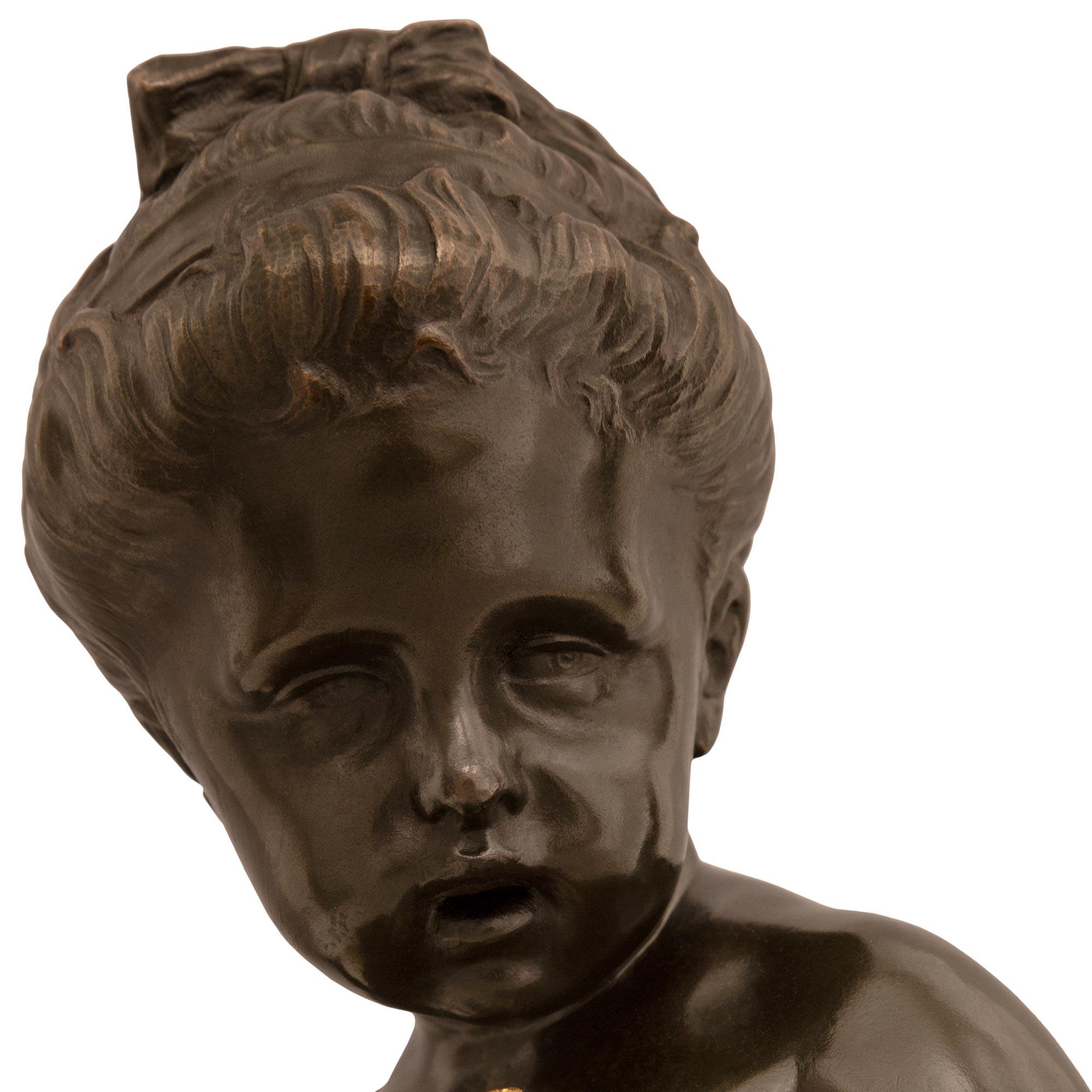 Un'affascinante statua in bronzo patinato e ormolu di un giovane cherubino del XIX secolo, di alta qualità. La statua è sollevata da una base quadrata in marmo Gris St. Anne su alzate in Ormolu. Sui quattro lati del piedistallo sono presenti rosette
