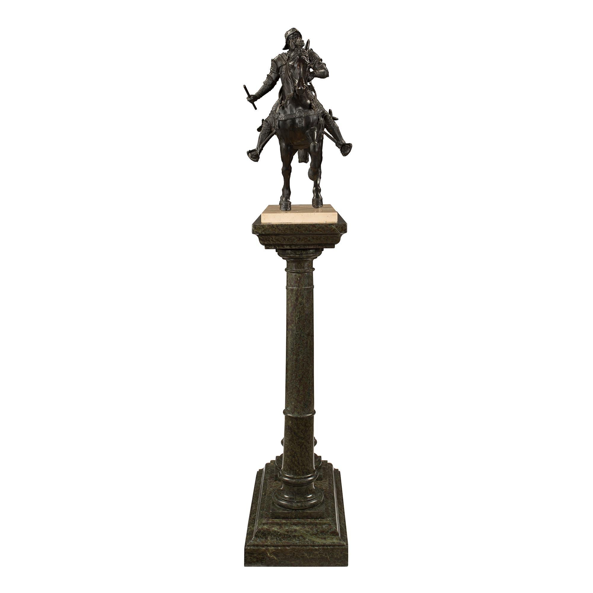 A handsome French 19th century Louis XVI st. patinated bronze soldier on his horse. The statue rests on its original double column marble pedestal. The pedestal is raised by the thick green marble mottled rectangular base below the two turned marble