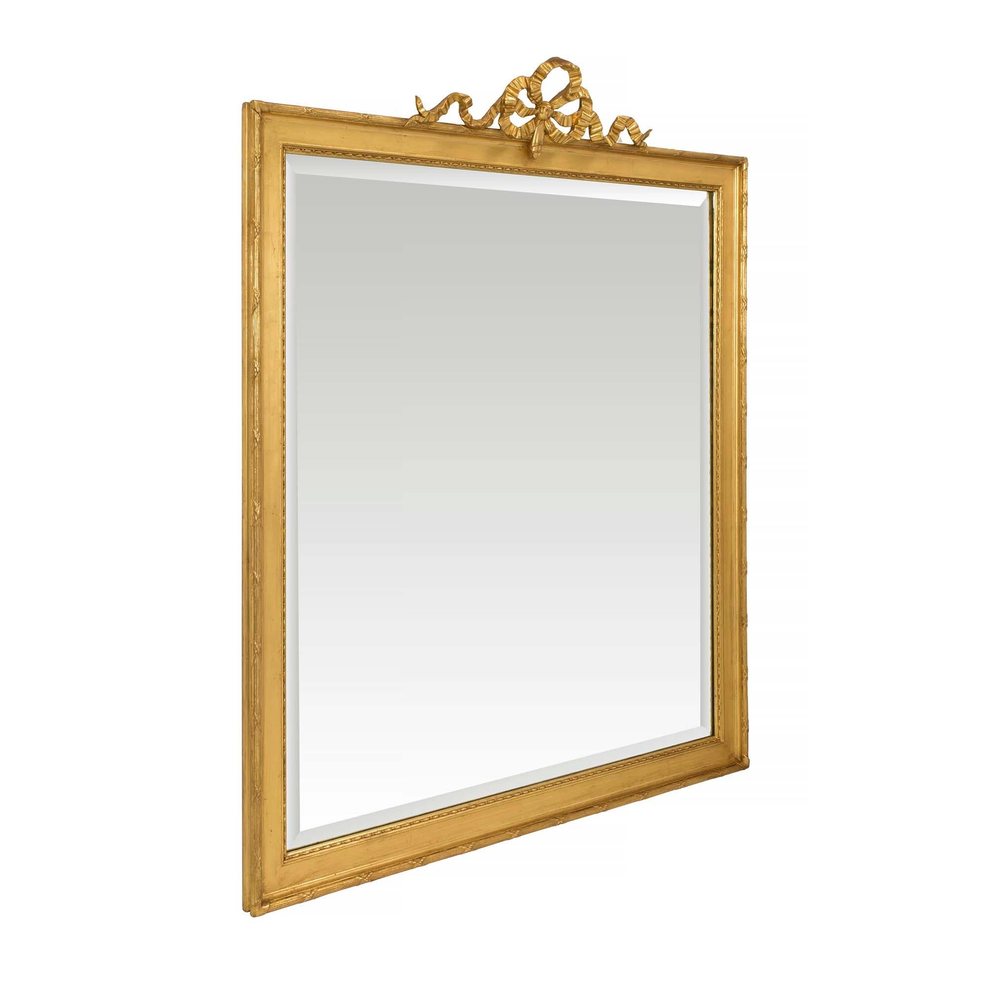 An elegant French 19th century Louis XVI st. rectangular giltwood mirror. The beveled mirror plate is framed within a fine carved pattern and a mottled giltwood frame in a beautiful satin and burnished finish. At the border is a most decorative tied