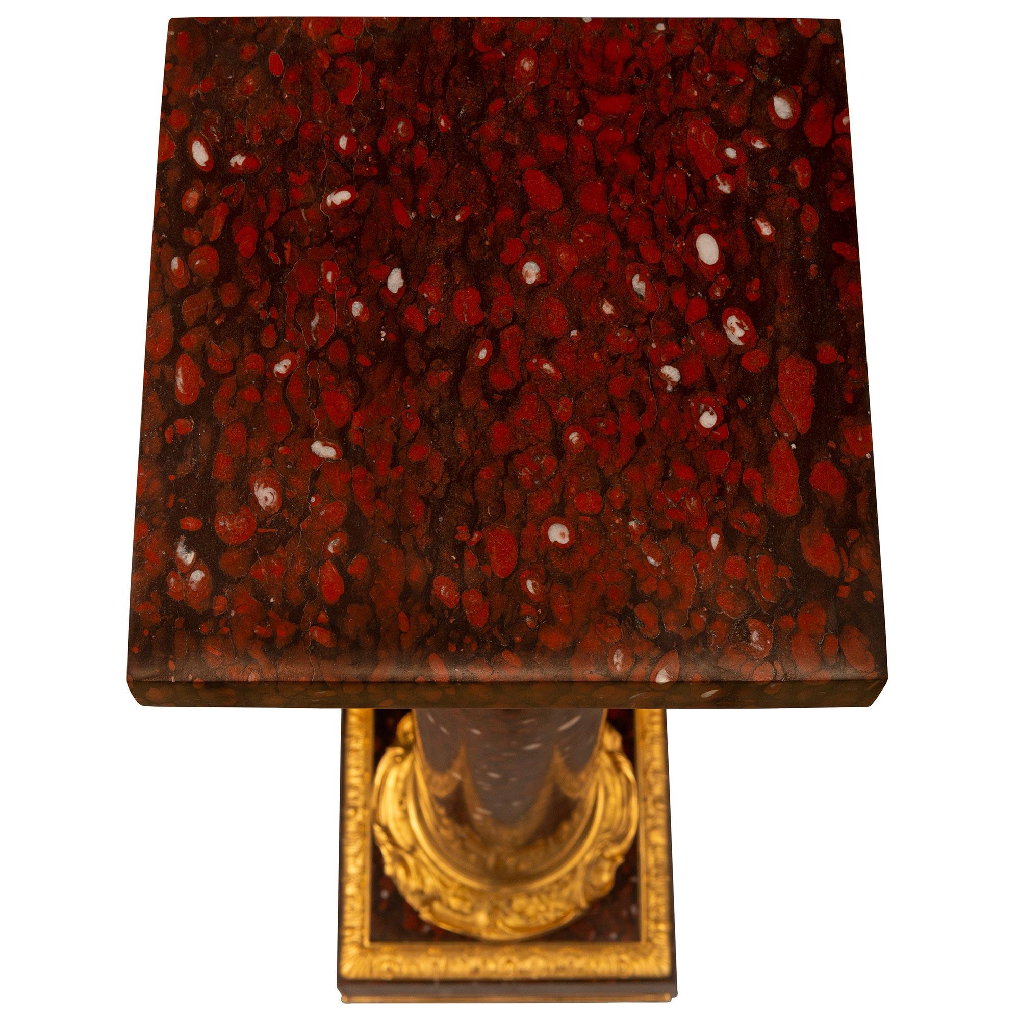 A striking French 19th century Louis XVI st. Rouge Griotte marble and Ormolu pedestal column. The column is raised by a square Rouge Griotte marble base with an Ormolu upper edge with foliate designs. Above the base is a circular Ormolu plinth with