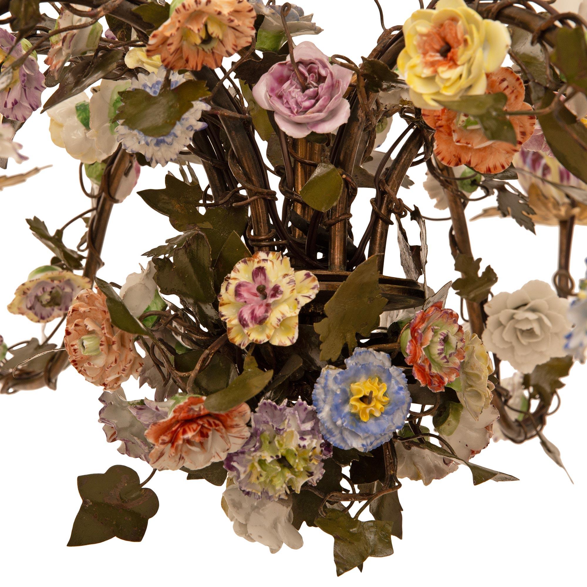 Un elegante e decoratissimo lampadario francese del XIX secolo in porcellana e tole di Saxe. Questo splendido lampadario a sei bracci è centrato in basso da una serie di bellissimi e coloratissimi fiori in fiore con i sei bracci a 