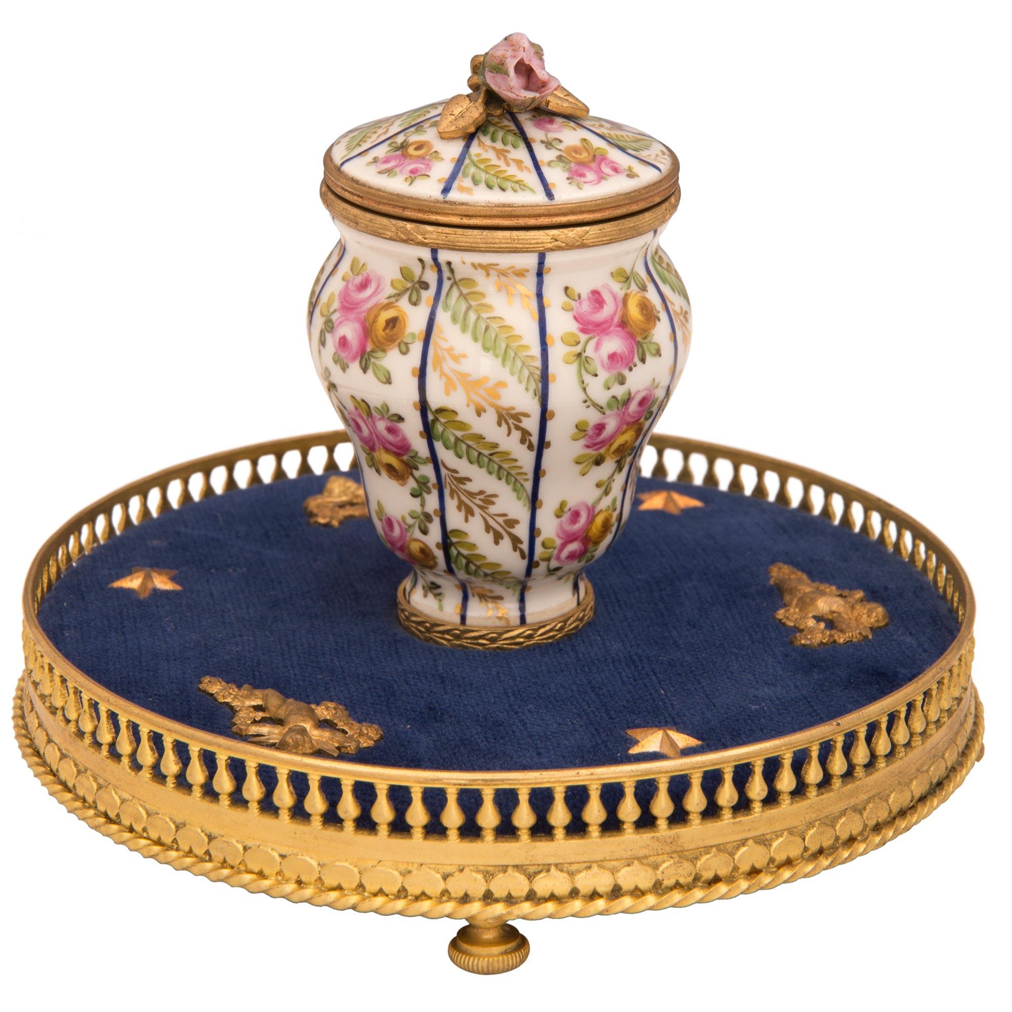 A charming and most elegant French 19th century Louis XVI st. Sèvres Porcelain and ormolu inkwell, stamped, P.C.G. The inkwell is raised by Fine fluted bun shaped feet below the beautiful wrap around ormolu gallery. The gallery displays a