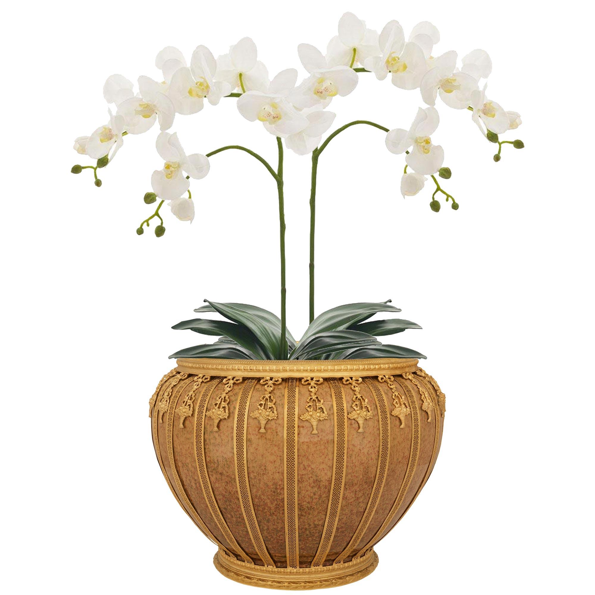 Un grazioso e unico vaso/pianta in porcellana e ormolu di Sèvres del XIX secolo. Questo splendido vaso è sollevato da uno zoccolo in Ormolu a due gradini che sostiene il corpo in porcellana di Sévres screziata di rosa e verde. Il corpo è decorato