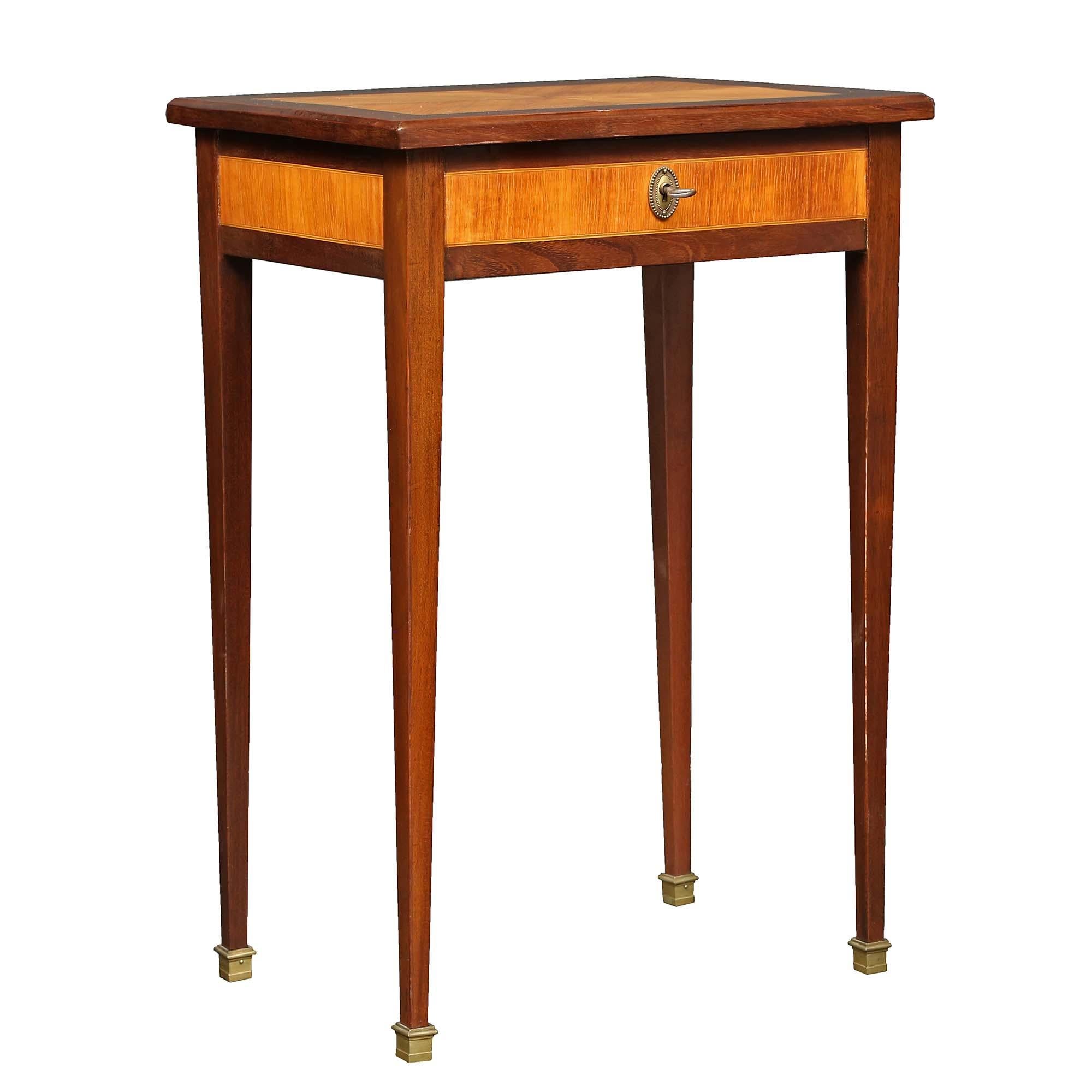 A charming French 19th century Louis XVI st. tulipwood, charmwood and kingwood side/vanity table. The table raised on straight legs has a quarter veneered tulip wood top bordered by charm wood and ormolu sabots. The top lifts up to a divided