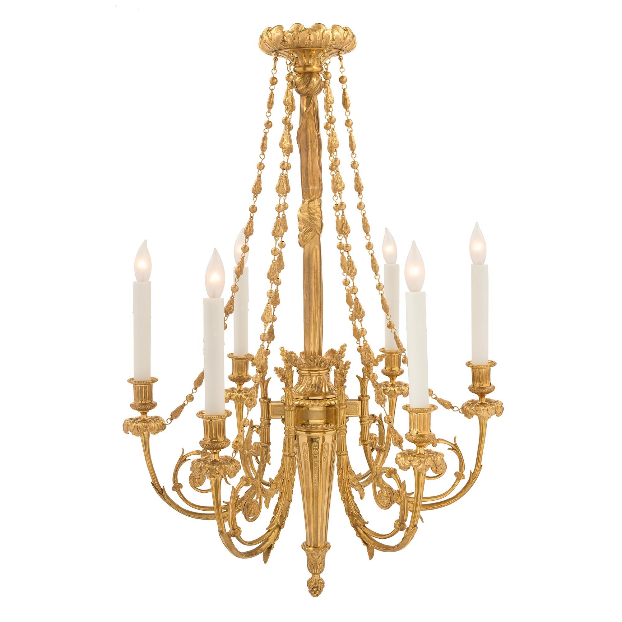 Un lustre à six bras de lumière en bronze doré de style Louis XVI du 19ème siècle, extrêmement élégant. Le lustre est centré par un fin gland inversé inférieur sous le support cannelé effilé. Chaque bras présente une belle forme Rinceau à volutes