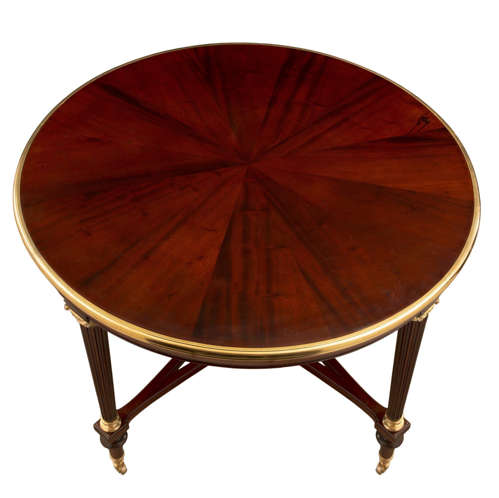 An extremely elegant pair of French 19th century Louis XVI st. solid mahogany and ormolu center tables, attributed to Henry Dasson. Each table is raised by Fine elongated topie shaped feet with their original ormolu casters. Each of the slender