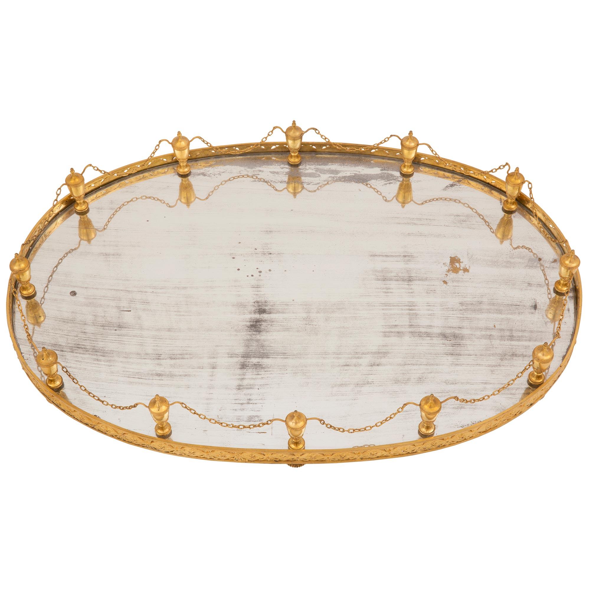 A magnificent French 19th century Louis XVI st. ormolu and mirrored Surtout de Table centerpiece. The centerpiece is raised by ten elegant topie shaped feet with fine beaded designs. The original central mirror plate is framed within a striking
