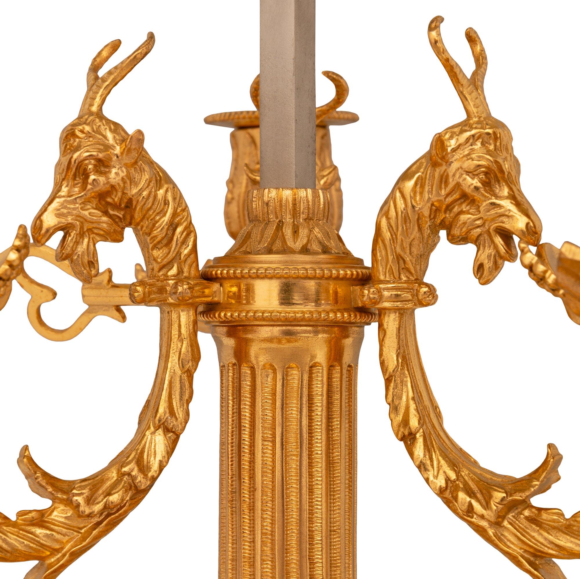 Lampe Bouillotte en tôle et bronze doré de grande qualité et finement décorée, de style Louis XVI, du 19e siècle. Cette exquise lampe à trois bras et deux lumières est soutenue par une base circulaire percée avec des motifs en spirale enveloppants.
