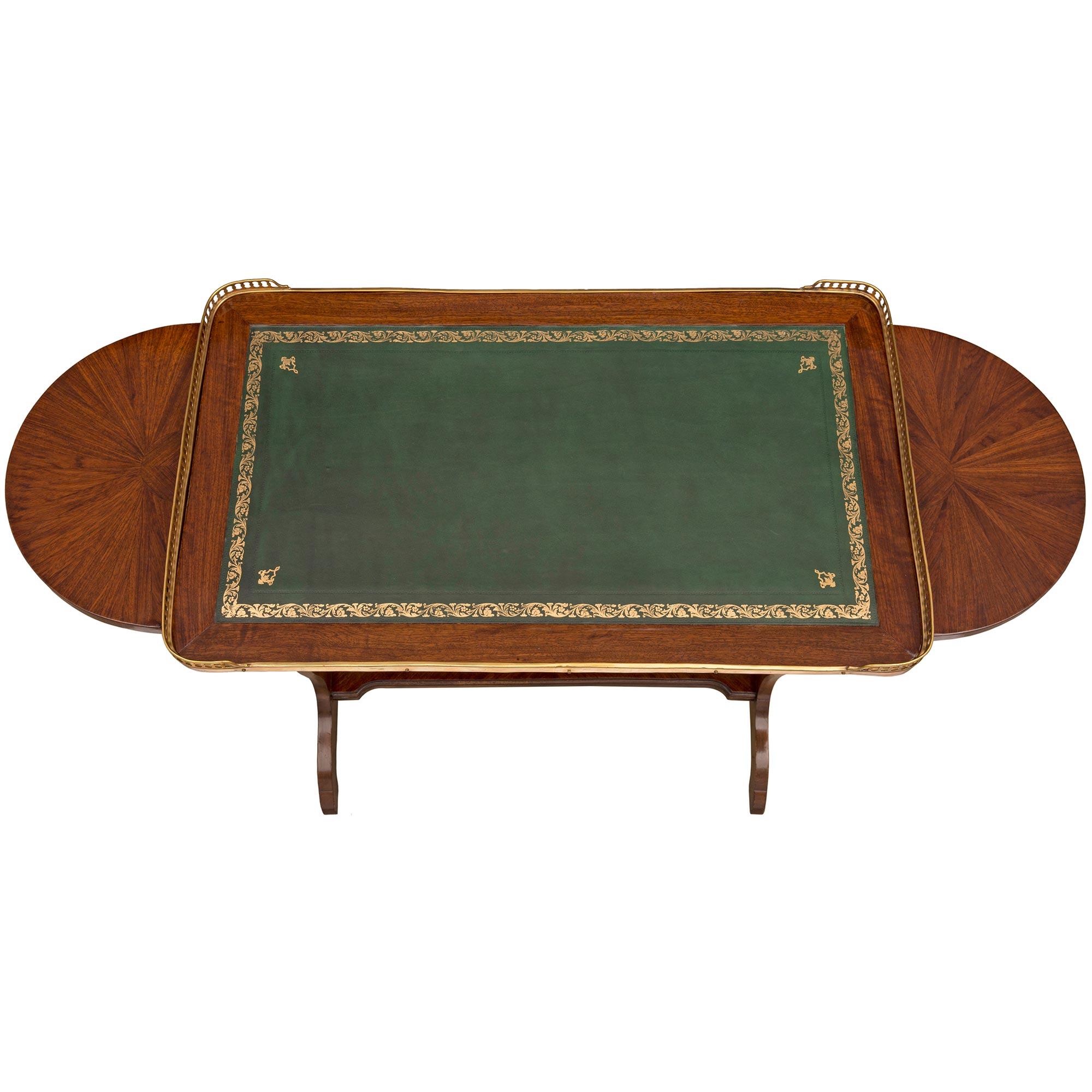 An elegant French 19th century Louis XVI st. tulipwood and ormolu side table. The table is raised by Fine arched feet below the beautifully shaped pierced supports each connected by a straight mottled stretcher. Above is the gold tooled green