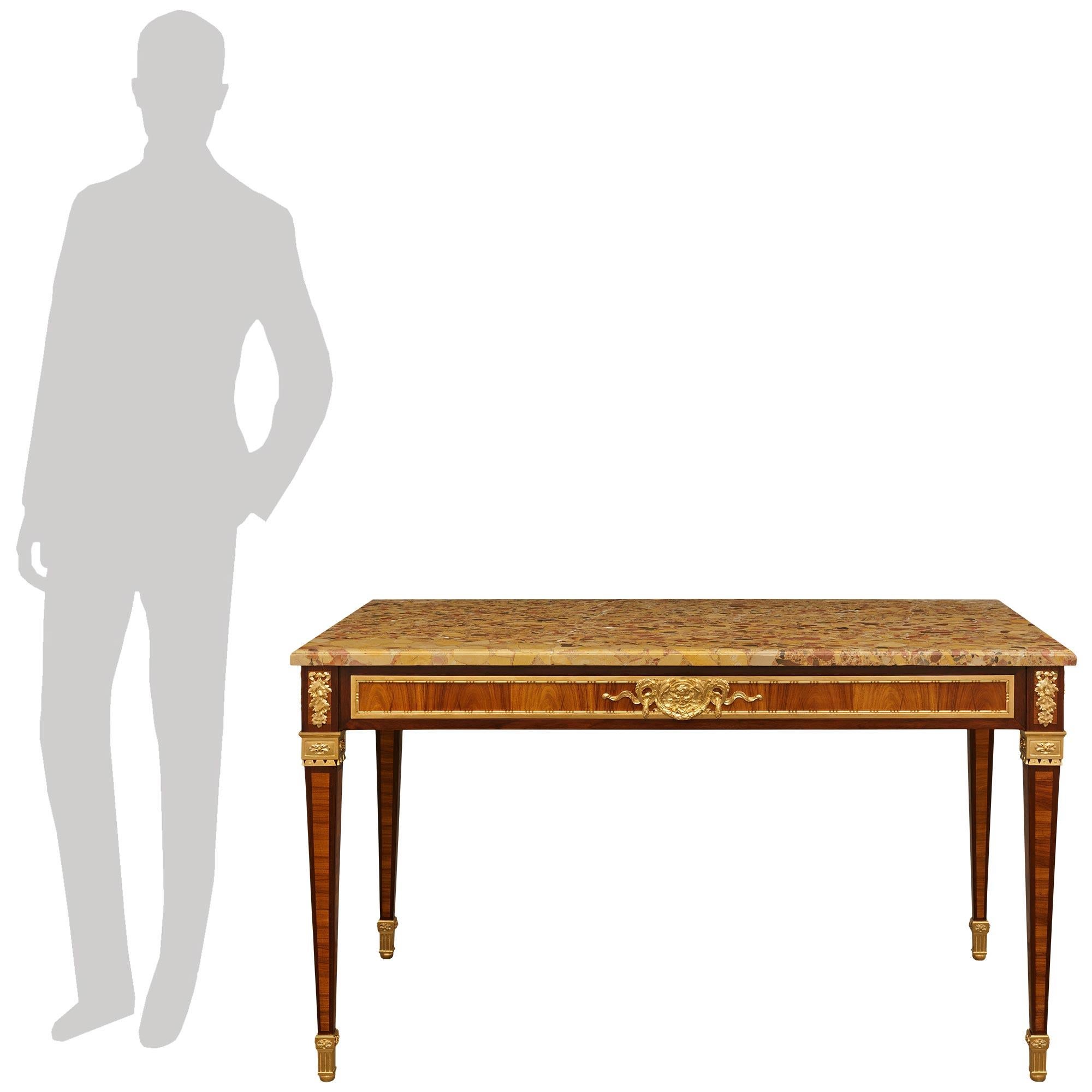 Magnifique table de centre en bois de tulipier, bois de roi, bronze doré et marbre brèche d'Alep, de style Louis XVI, du milieu du 19e siècle. Cette superbe table rectangulaire repose sur quatre pieds fuselés carrés qui se terminent par