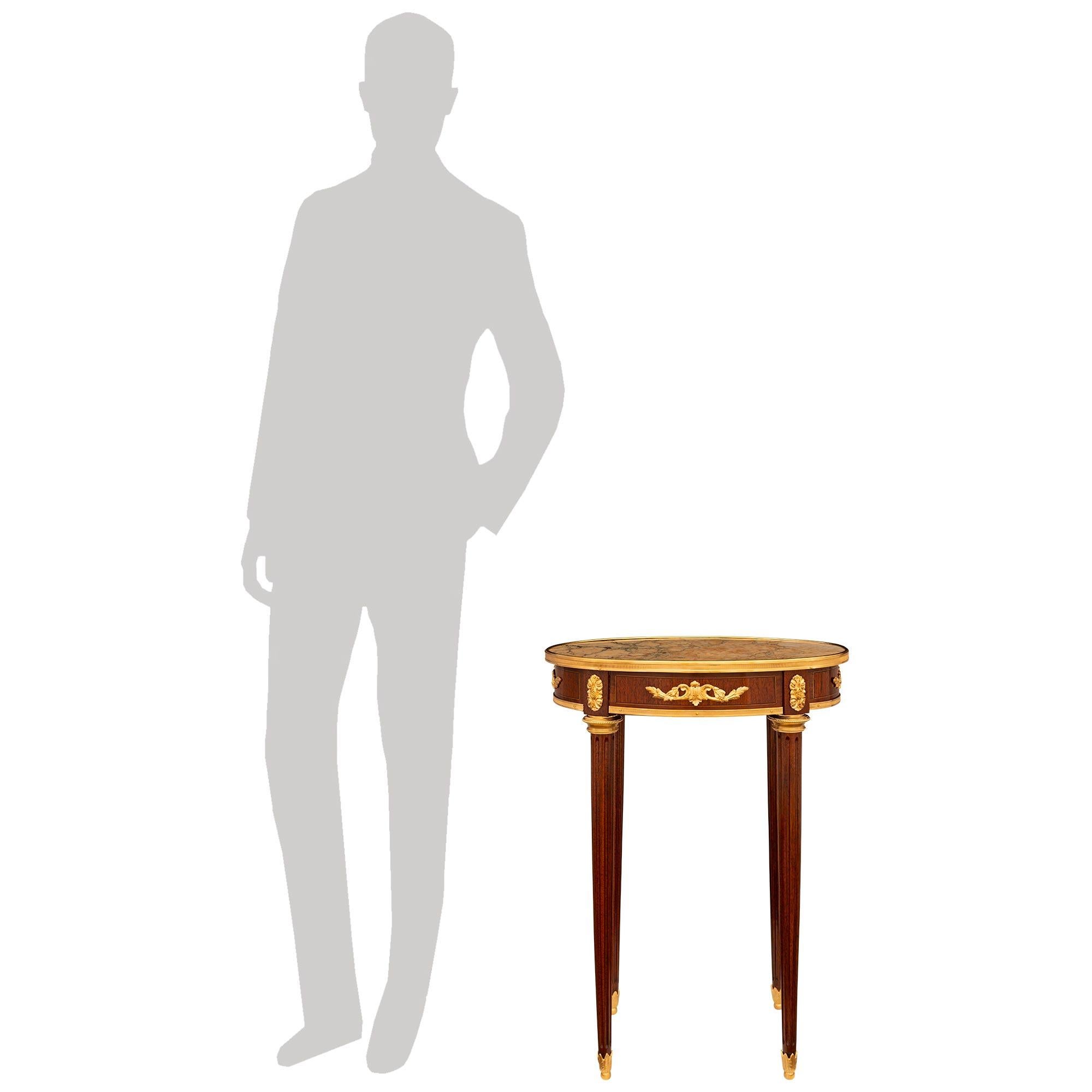 Charmante et très élégante table d'appoint en bois de tulipier, bronze doré et marbre brèche rouge de style Louis XVI du XIXe siècle. Cette magnifique table d'appoint ovale repose sur quatre pieds cannelés effilés et est soutenue par des sabots