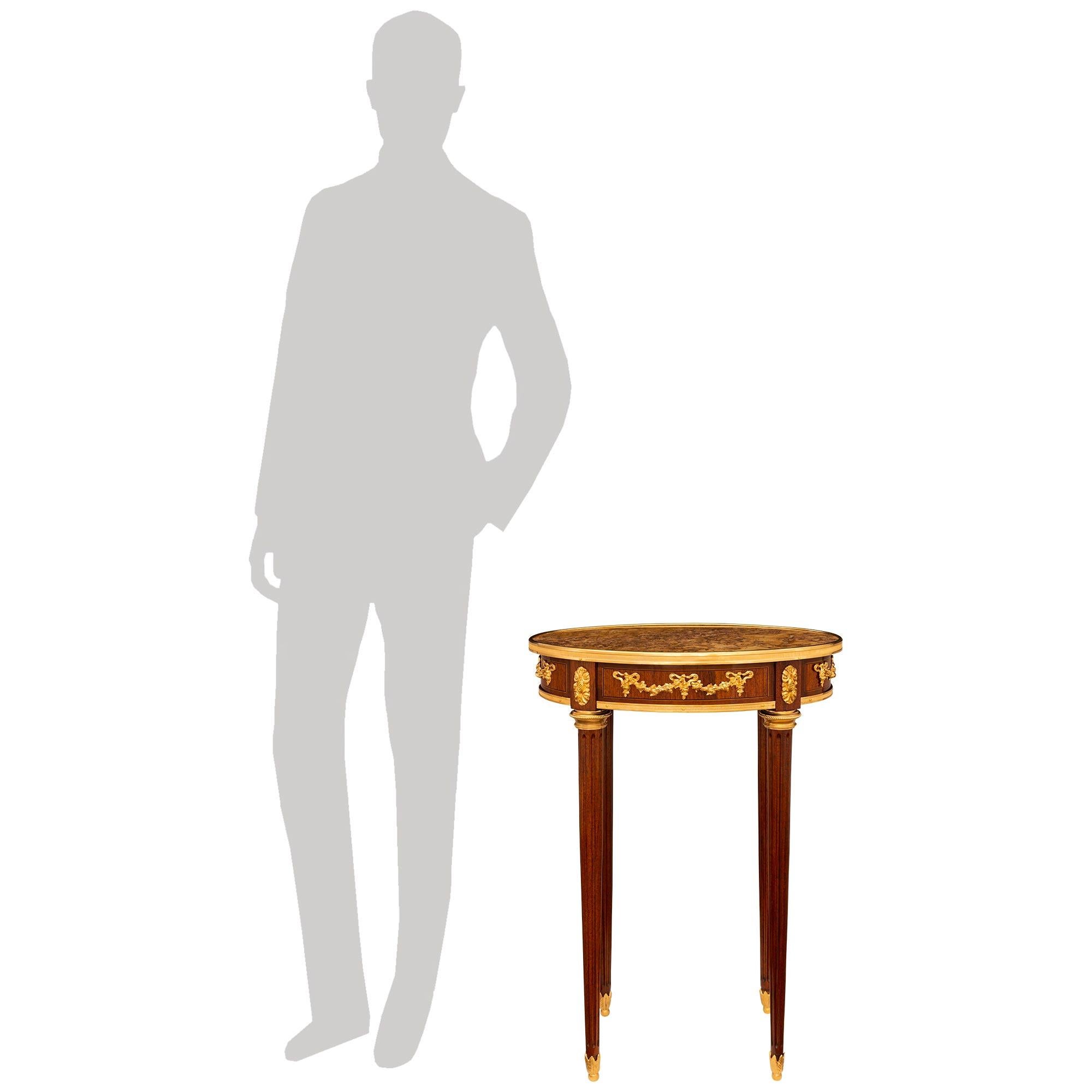 Magnifique et très élégante table d'appoint en bois de tulipier, bronze doré et marbre brèche rouge de style Louis XVI du XIXe siècle. Cette jolie table ovale repose sur quatre pieds fuselés et cannelés qui sont soutenus par des pieds boules en
