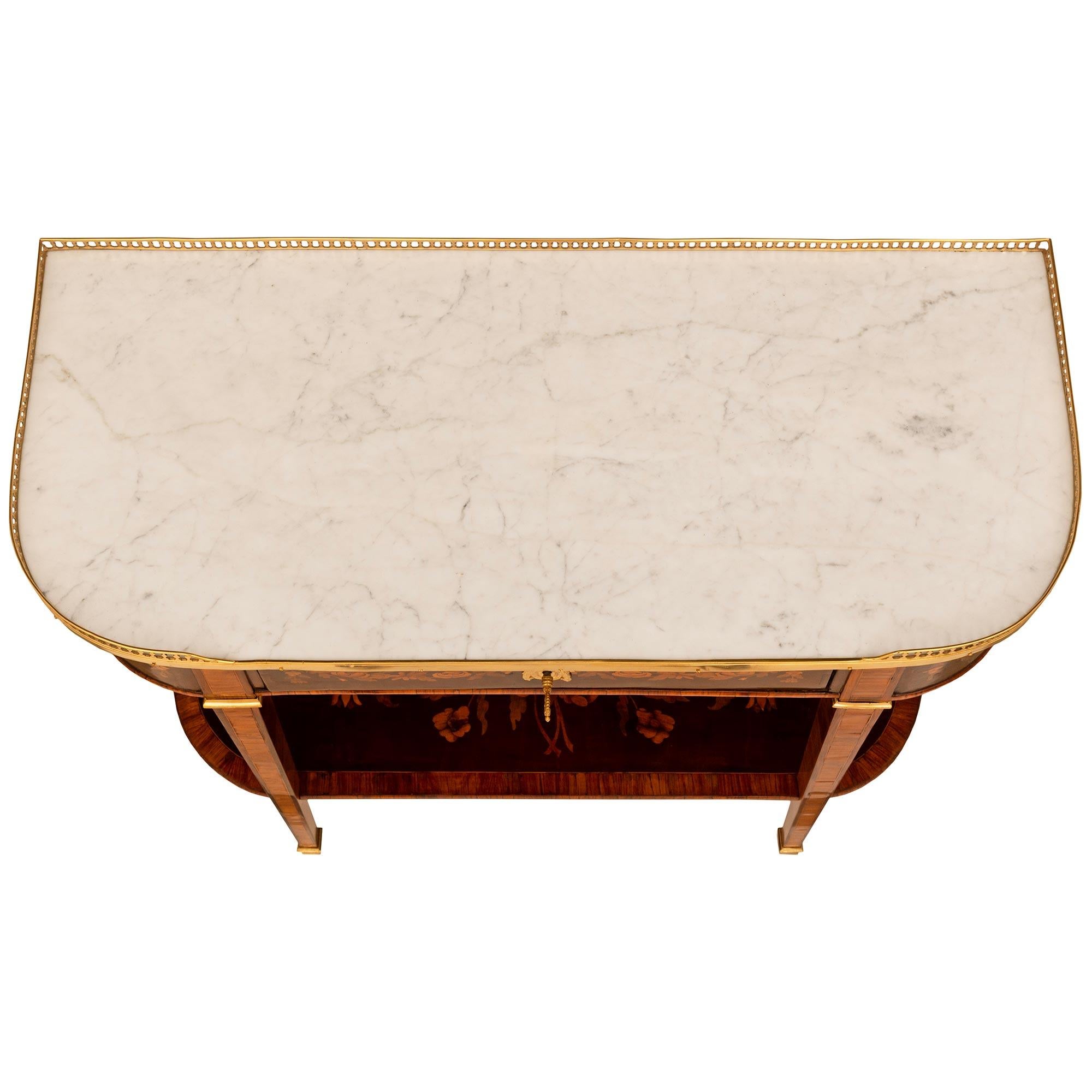 A stunning French 19th century Louis XVI st. Tulipwood, Walnut, Ormolu and white Carrara marble console. The demi lune shaped console is raised on four square tapered legs with Ormolu sabots extending up to a single display tier decorated with a