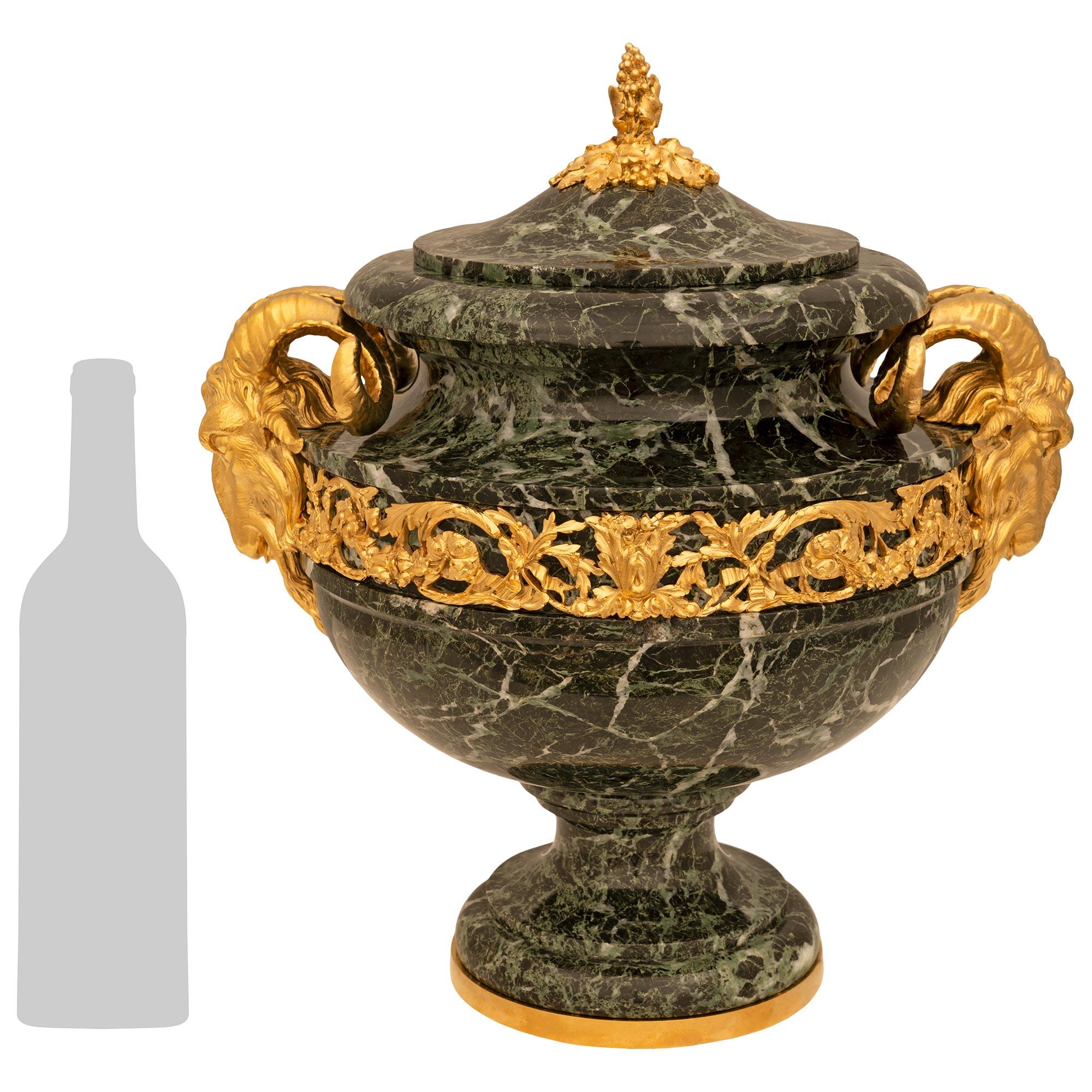 Un'imponente e decoratissima urna francese del XIX secolo in stile Luigi XVI Vert de Patricia e Ormolu. L'urna è sollevata su una base circolare in Ormolu al di sotto del supporto in marmo Vert de Patricia. L'urna sovrastante ha una fascia