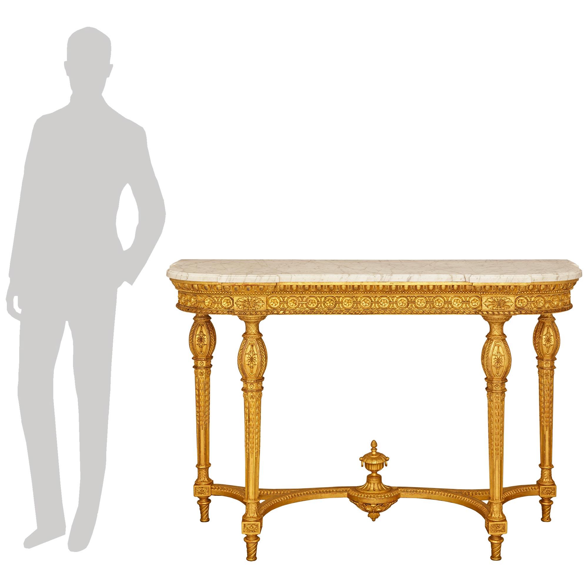 Un'elegantissima console francese del XIX secolo in stile Luigi XVI in marmo bianco di Carrara e legno d'orato. Questa bellissima consolle indipendente è sollevata da quattro gambe tonde e affusolate e poggia su piedi scanalati a spirale. Tutte e