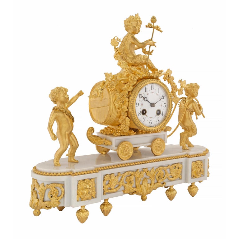 An elegant and high quality French 19th century Louis XVI st. white Carrara marble and ormolu clock. The clock is raised by foliate topie shaped feet below the oblong shaped white Carrara marble base. The base displays a fine fitted pierced ormolu
