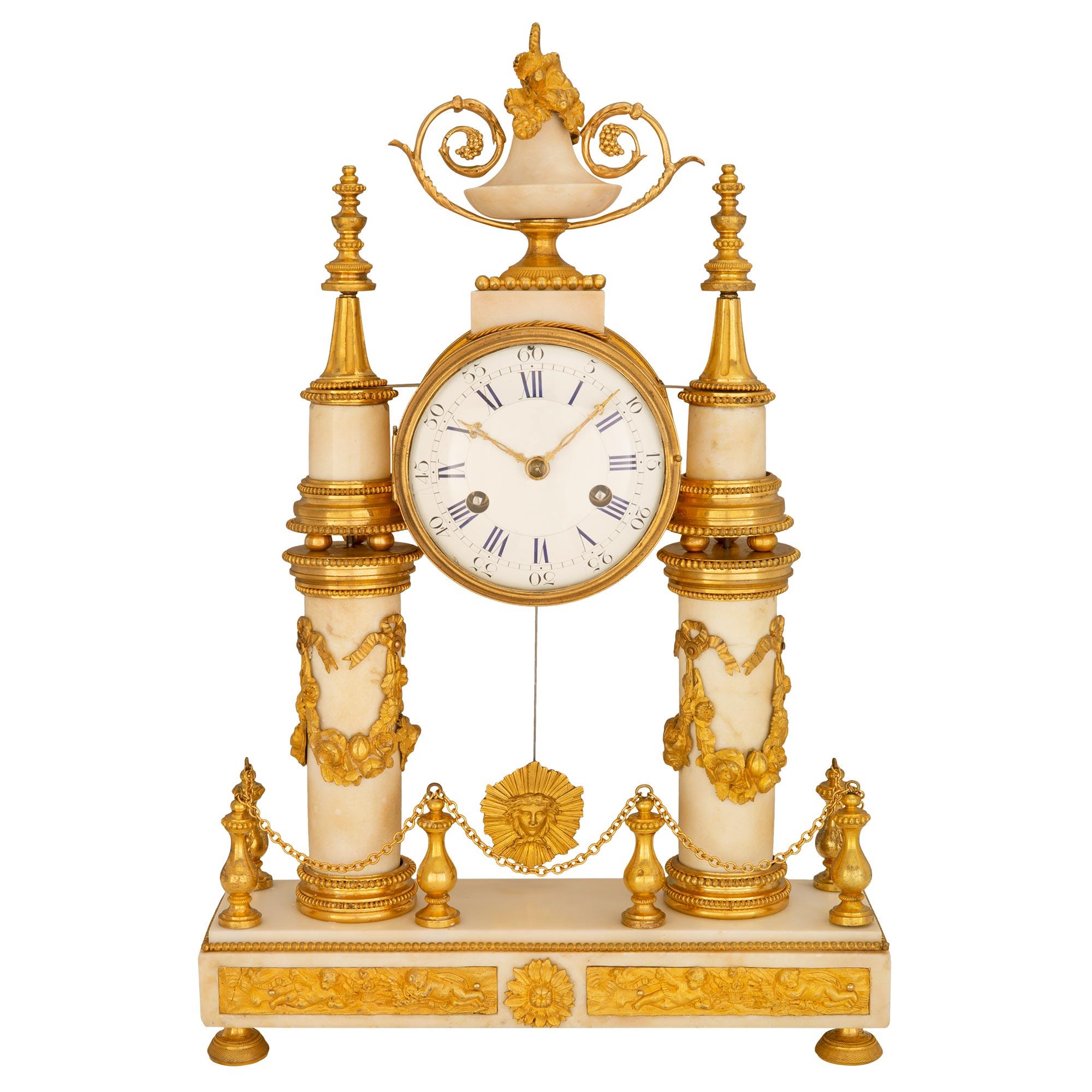 An exquisite French early 19th century Louis XVI st. white Carrara marble and ormolu mounted clock. Raised on ormolu supports the rectangular marble base with beaded trim and Clodion style plaques is centered by a floral mount. Above ormolu