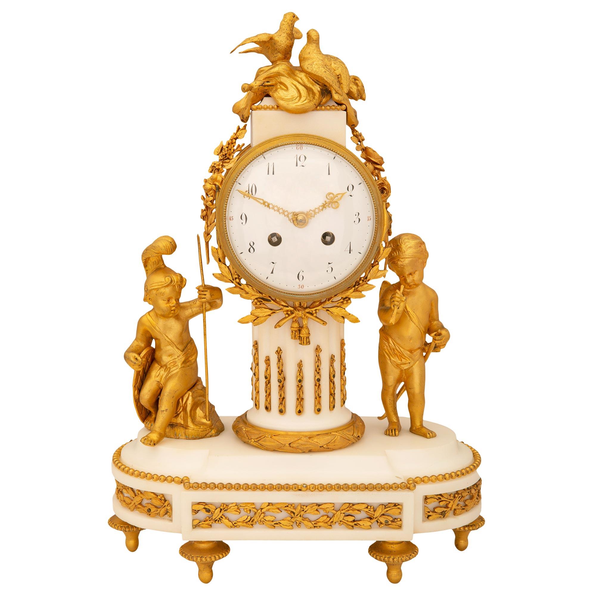 An exquisite French 19th century Louis XVI st. white Carrara marble and ormolu clock. The clock is raised by ormolu topie shaped supports below a marble base with ormolu scrolling foliage and ormolu beaded row. Above is the central fluted marble