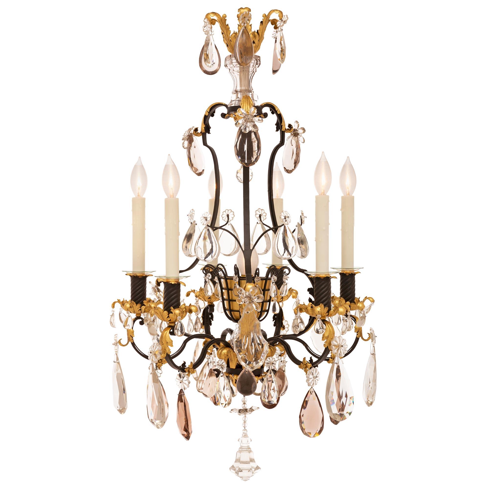 An exceptional and very unique French 19th century Louis XVI st. wrought iron, gilt metal, and crystal chandelier likely by Maison Bagues. The six arm seven light chandelier is centered by a charming and most unique bottom crystal pendant below