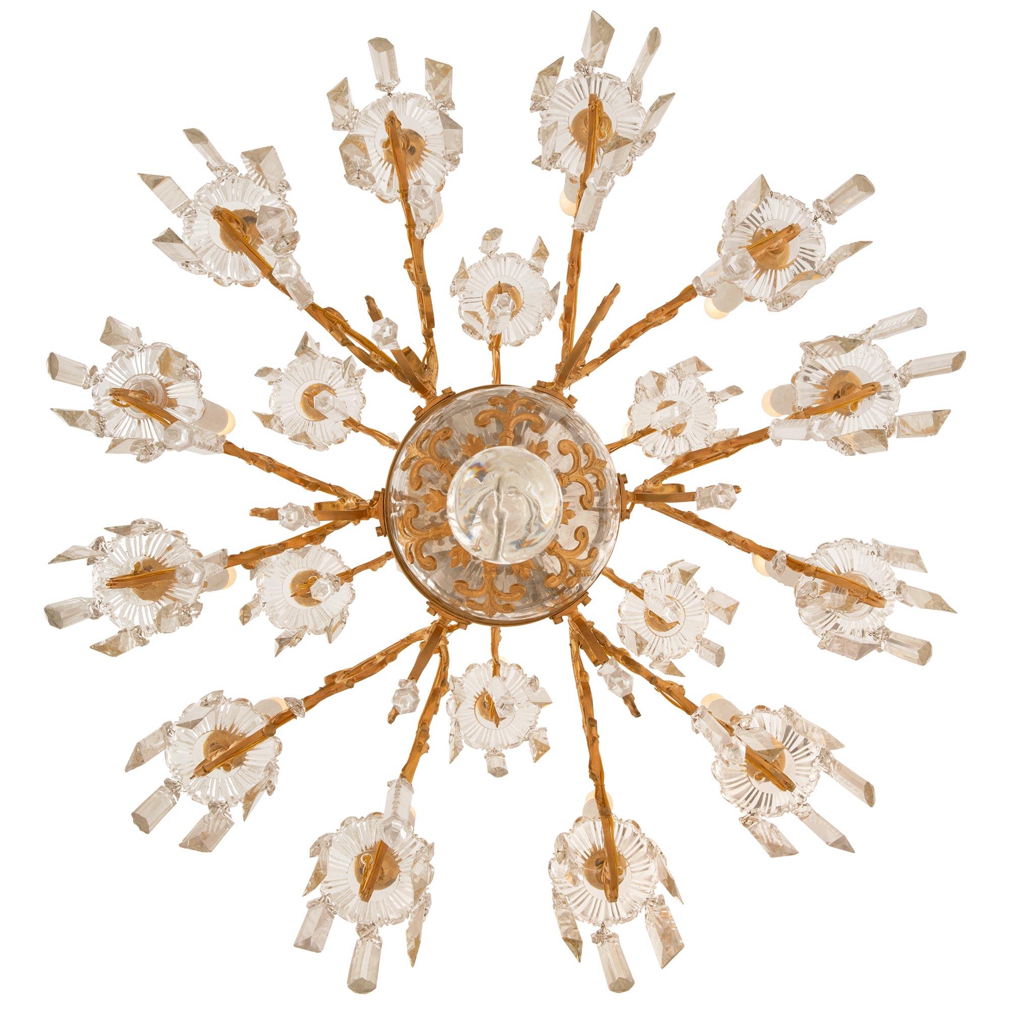 A stunning French 19th century Louis XVI st. Baccarat crystal and ormolu eighteen light chandelier. This unique chandelier is centered by a solid crystal ball leading up to a richly chased ormolu finial, below a large crystal sphere with pierced