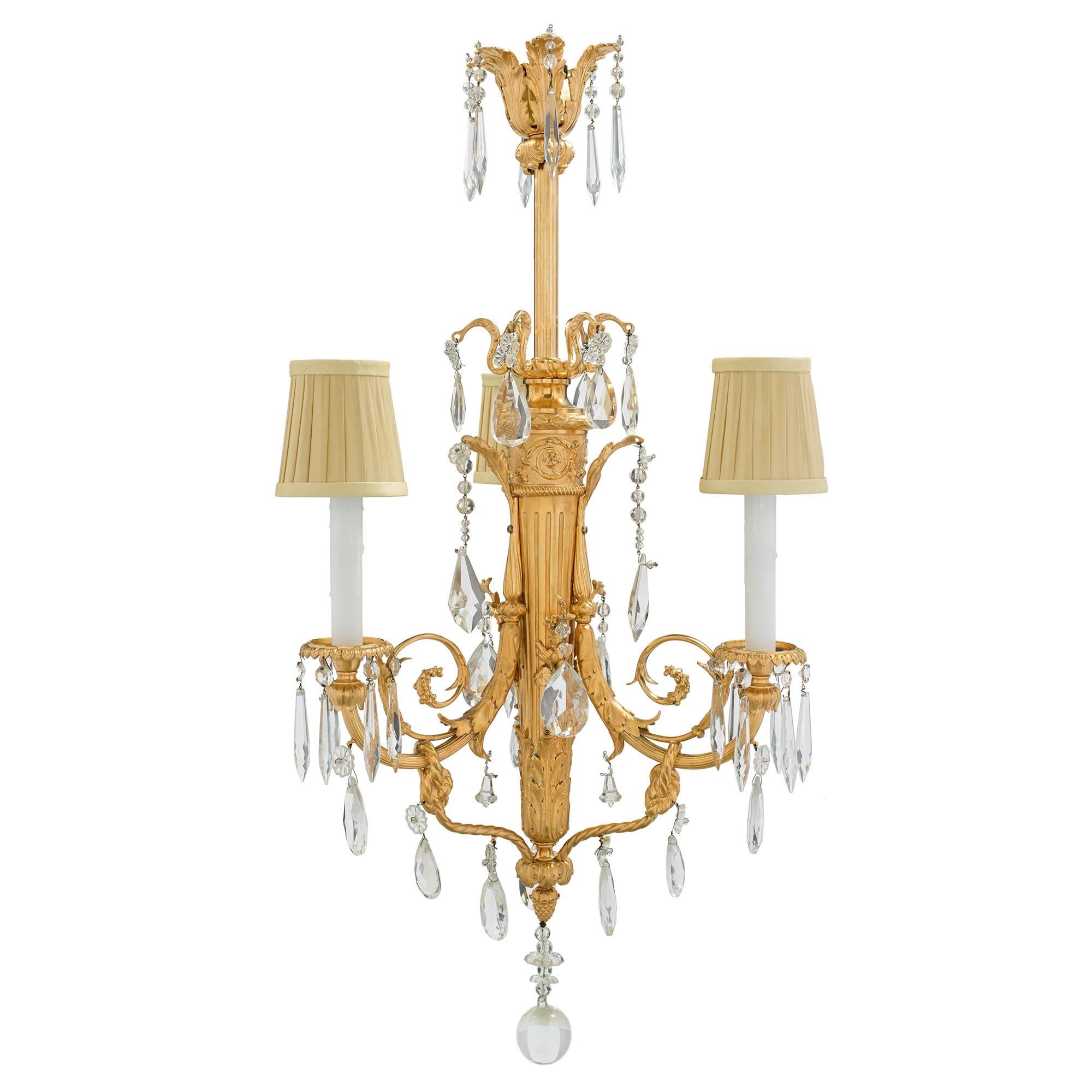 A lovely and very elegant French 19th century Louis XVI st. Baccarat crystal and ormolu three light chandelier. Centered at the bottom is an inverted ormolu acorn finial supporting a large crystal sphere with rosettes and smaller spheres. Joining to