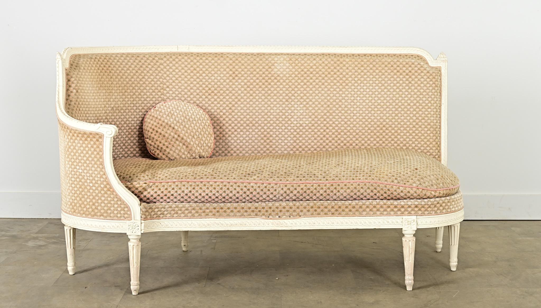 Una banquette (o piccolo divano occasionale) senza tempo di gusto Luigi XVI risalente al XIX secolo. La sua struttura in legno intagliato e dipinto protegge l'interno imbottito con un singolo cuscino da panca, uno schienale stretto e un singolo