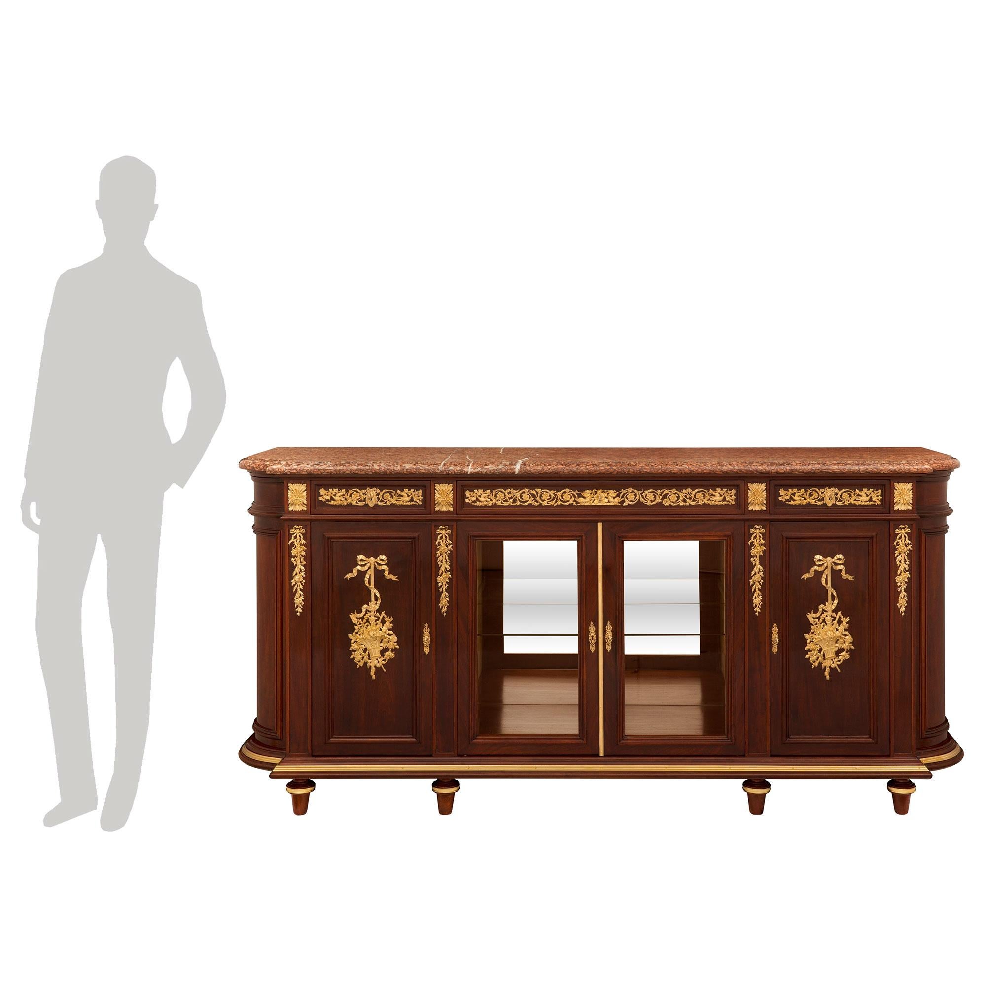 A stunning and extremely elegant French 19th century Louis XVI st. Belle Époque period mahogany, ormolu and Campan Rouge marble buffet, attributed to Maison Krieger. The four door, three drawer buffet is raised by fine circular tapered feet with