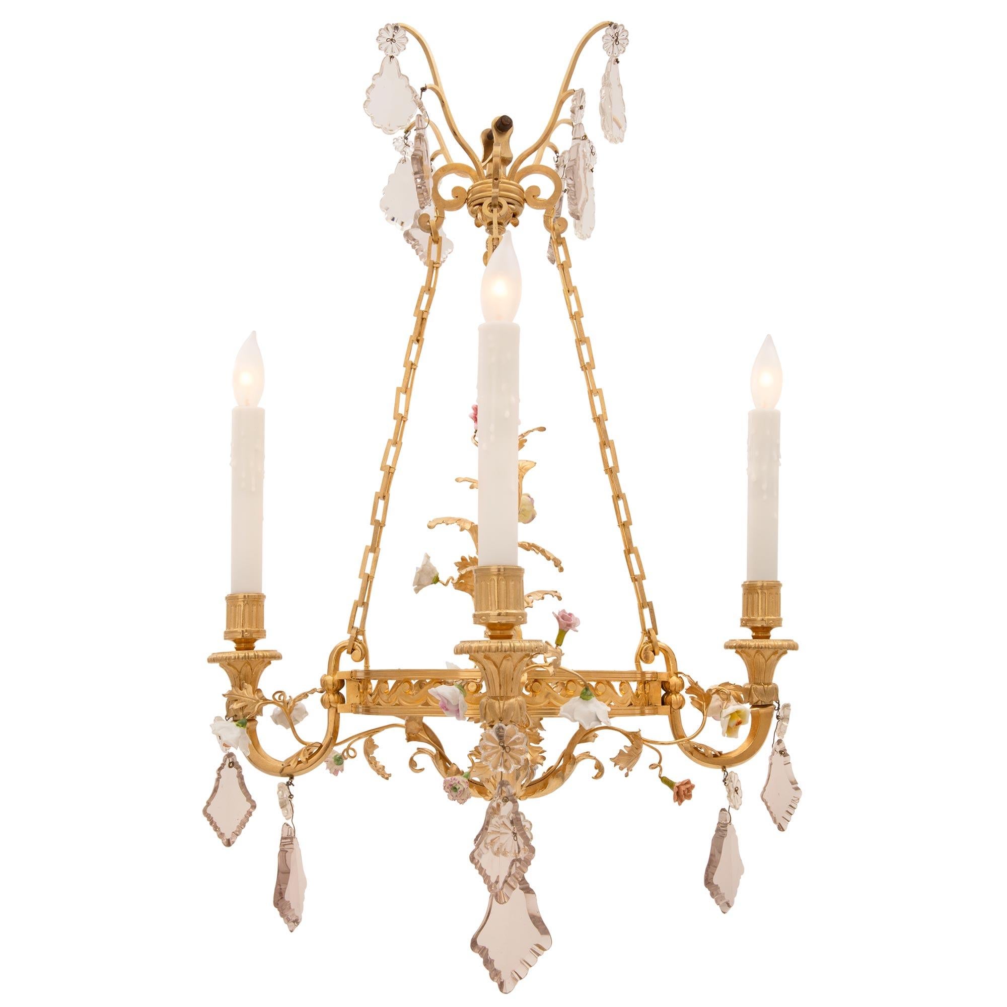 A striking and most elegant French 19th century Louis XVI st. Belle Époque period ormolu, Baccarat crystal and Saxe porcelain chandelier. The chandelier is centered by a lovely finely detailed bottom acorn finial below large decorative acanthus