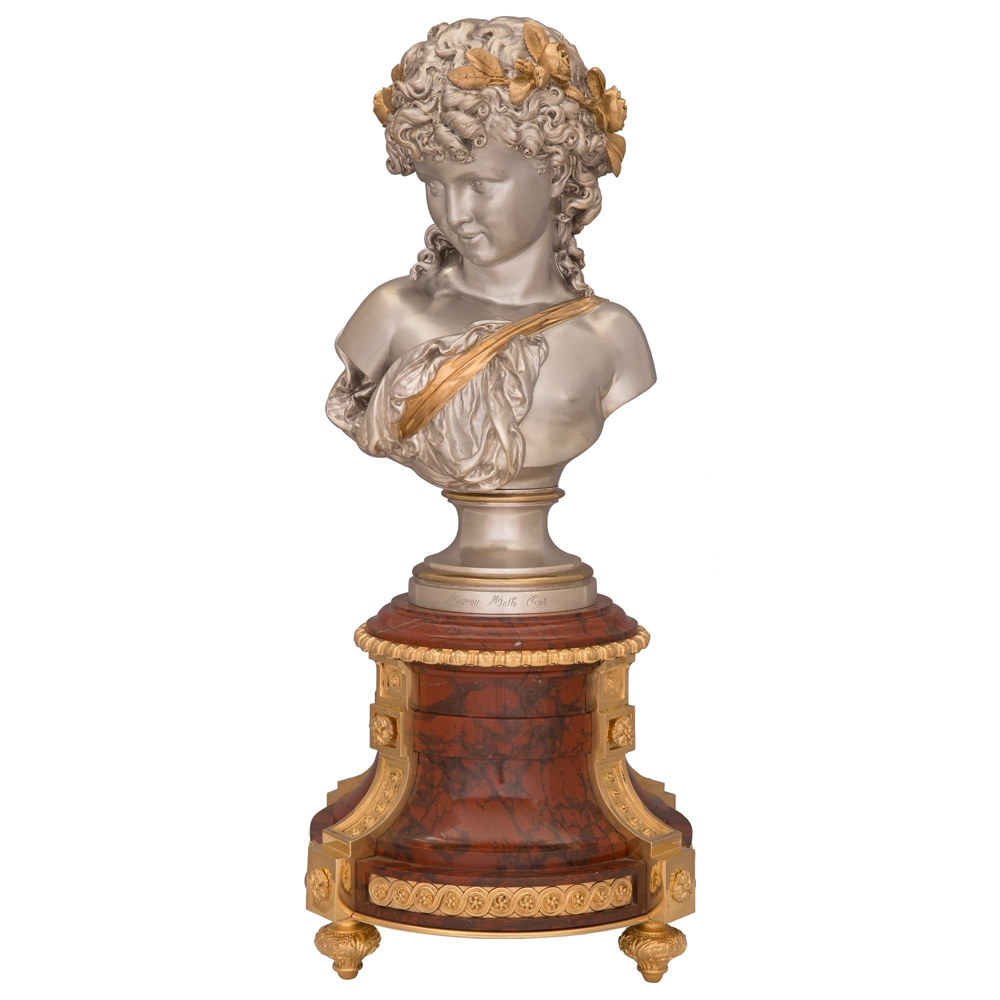 Remarquable garniture de style Louis XVI d'époque Belle Époque en bronze doré, bronze argenté et marbre Rouge Griotte. L'ensemble de garniture est composé de trois pièces, les deux pièces latérales étant surélevées par d'élégants pieds en bronze