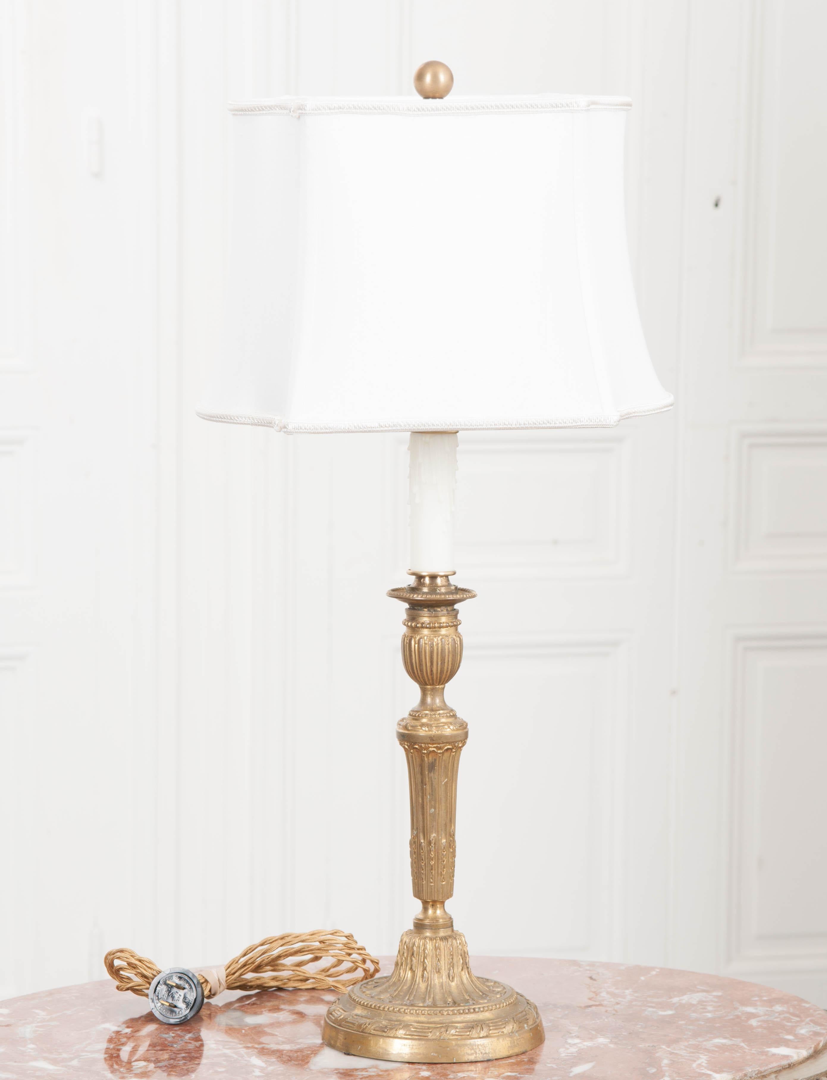 The standard for this diminutive single-light table lamp is a Louis XVI style reeded brass candlestick, circa 1860s, found in France. The custom shaped rectangular shade is ivory linen and topped with a brass ball finial. UL approved wiring for the
