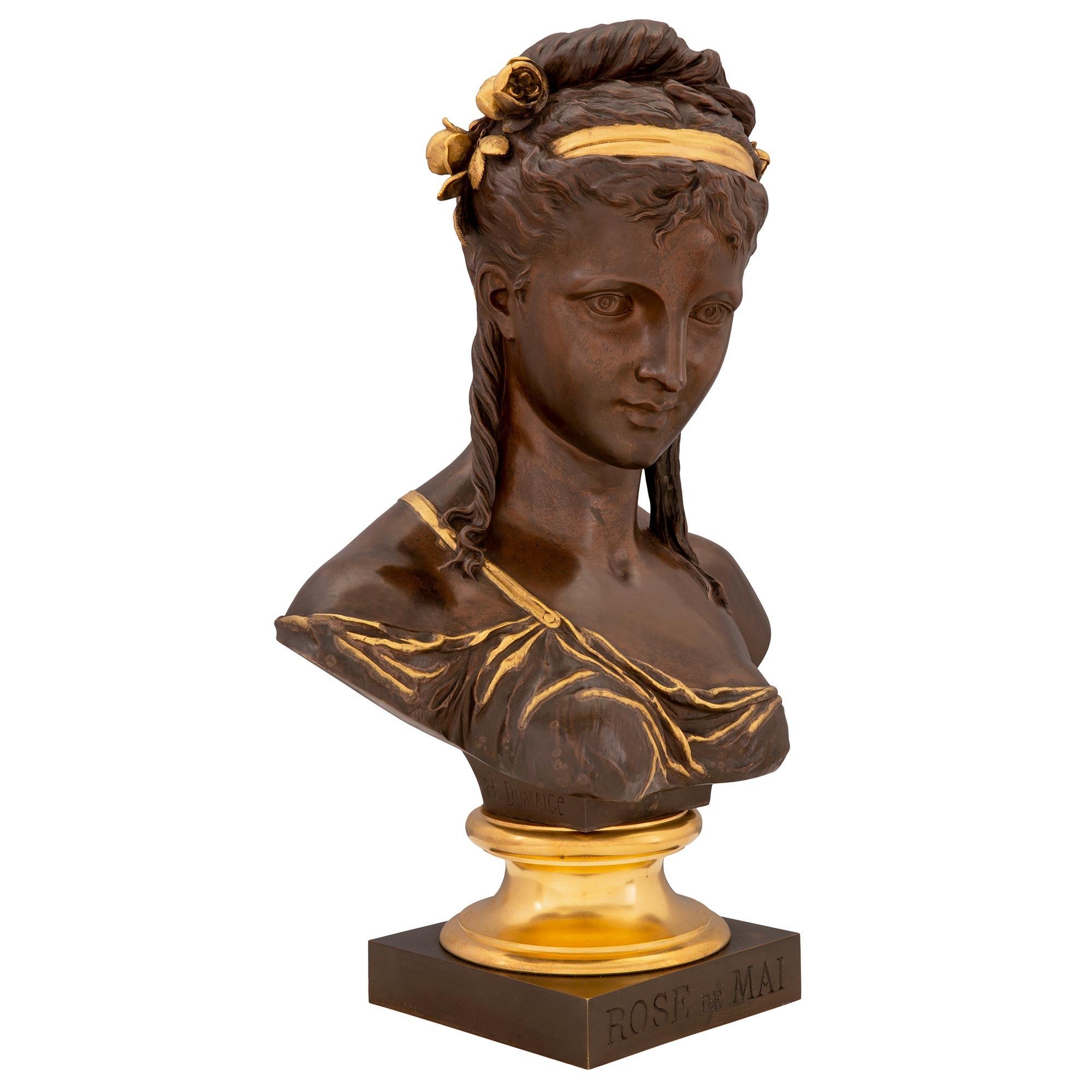 A stunning French 19th century Louis XVI st. patinated bronze and ormolu bust, signed H. DUMAICE. The bust is raised by a square patinated bronze base with the inscription ROSE de MAI with a mottled ormolu socle pedestal. The richly chased bust
