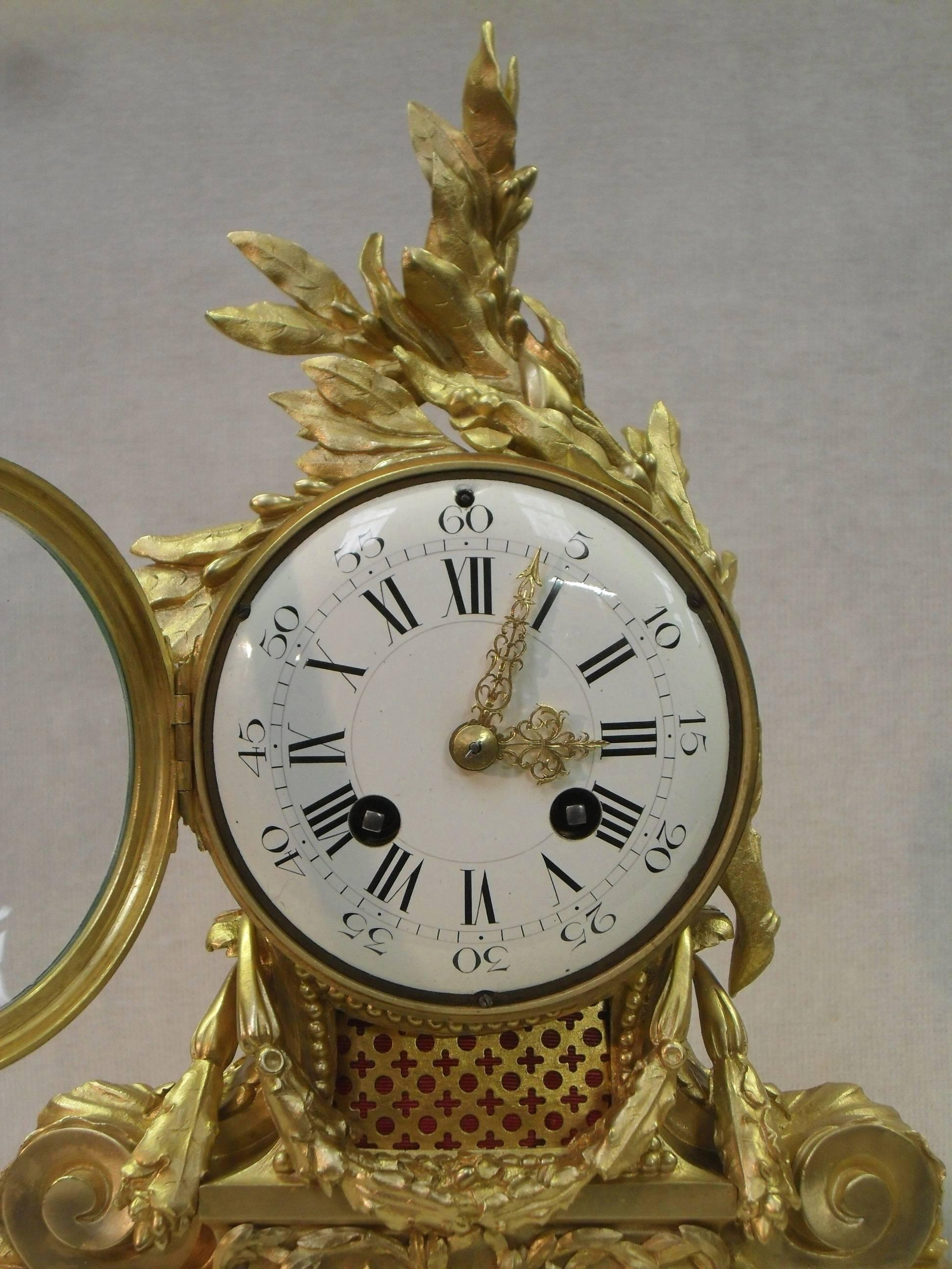 An extremely good quality French Louis XVI style bronze gilt mantel clock with scrolling foliate design, swags and beaded detail on shaped white Carrara marble base. The clock has a white enamel dial with French eight day movement which strikes the