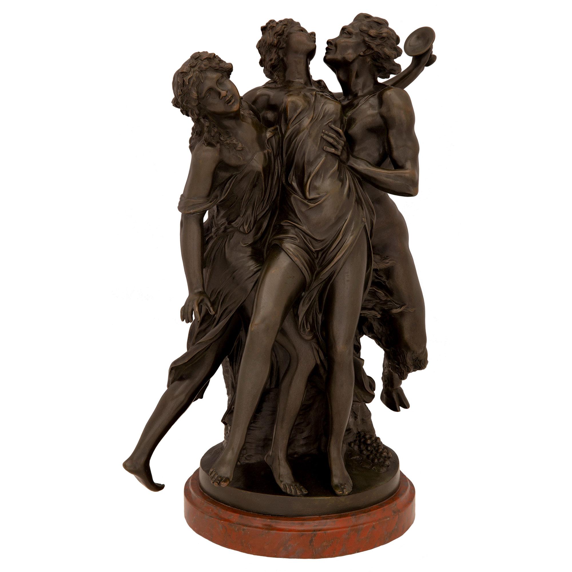 A striking French 19th century Louis XVI st. patinated bronze and faux painted Rouge Griotte Marble statue, after a model by Clodion. The statue is raised by a wonderfully executed circular faux painted Rouge Griotte marble base with a fine mottled